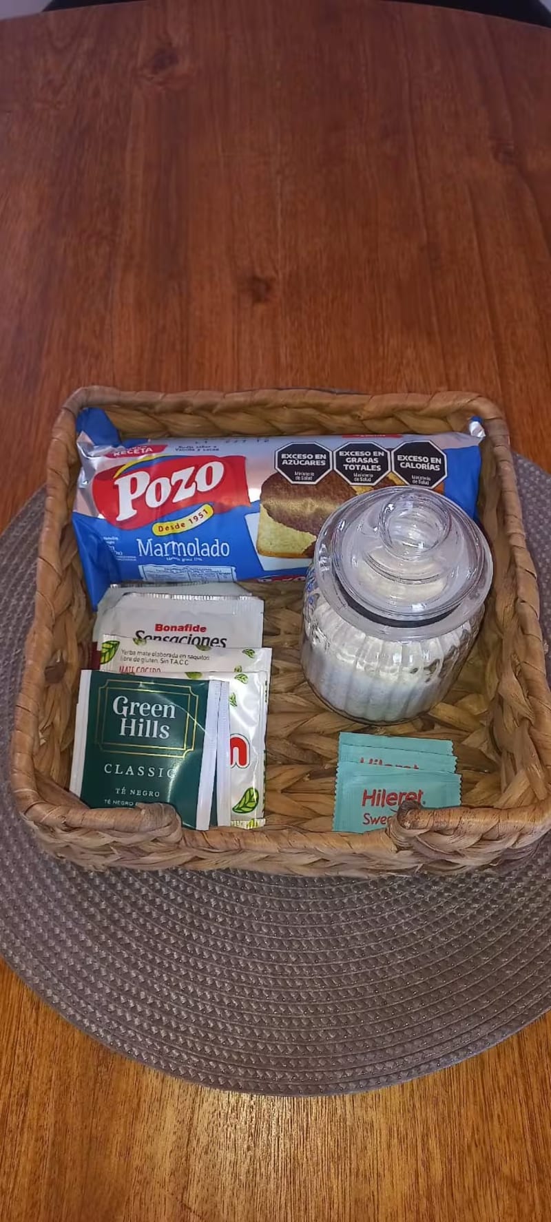 Canasta de mimbre con budín marmolado, frasco de azúcar, infusiones y edulcorantes de bienvenida