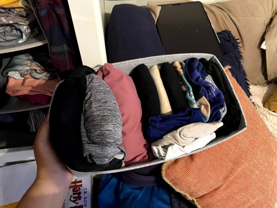 A small bin holding several pieces of undershirts. The shirts are neatly folded and packed tightly in the bin