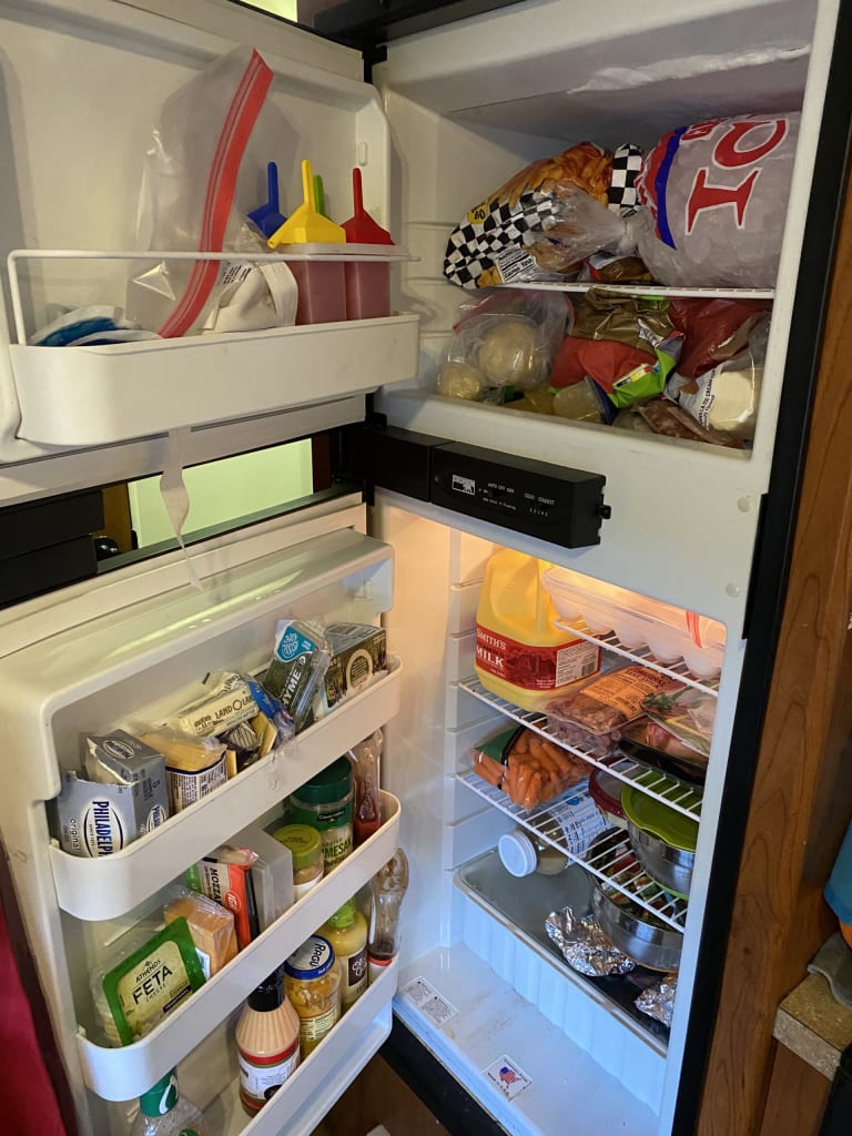 Our RV combo refrigerator and freezer. Both doors are open and full of food.