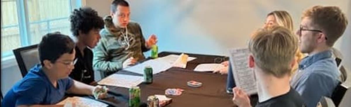 Teens gathered around a table playing a tabletop role-playing game during a social program event