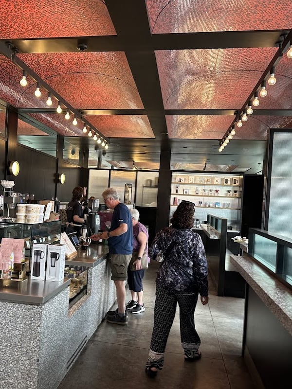 Interior of a modern cafe with a striking red patterned ceiling, customers ordering at the stone counter