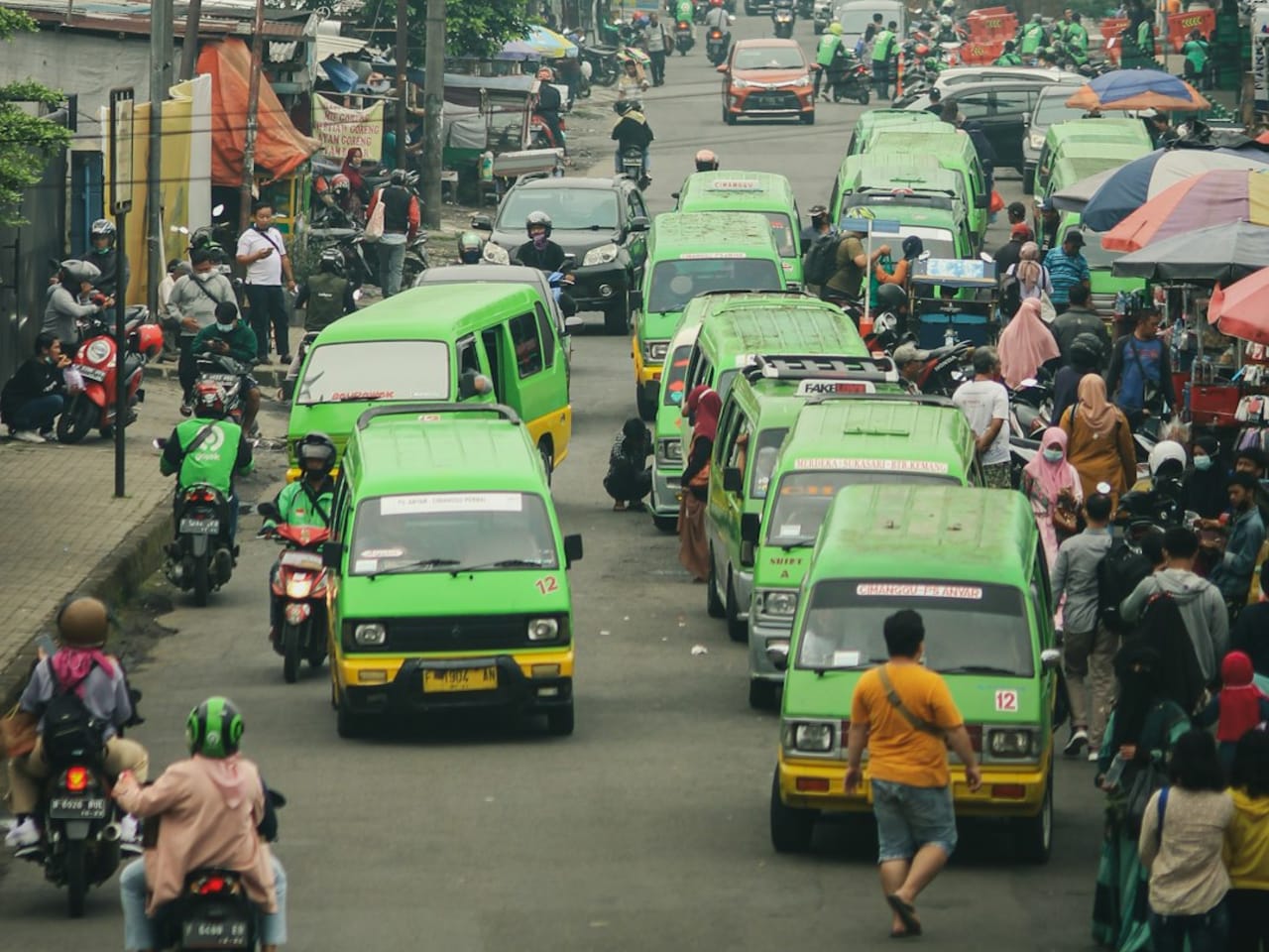 Jalanan ramai dengan kendaraan bermotor dan aktivitas lalu lintas yang padat di area perkotaan