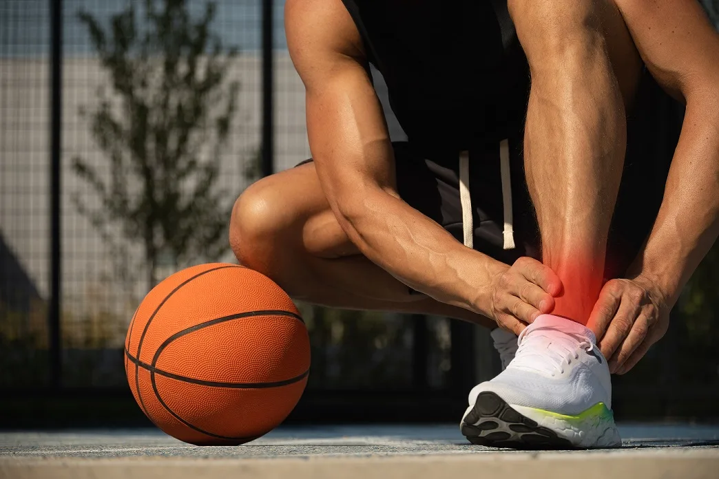 Basketball player holding ankle in pain