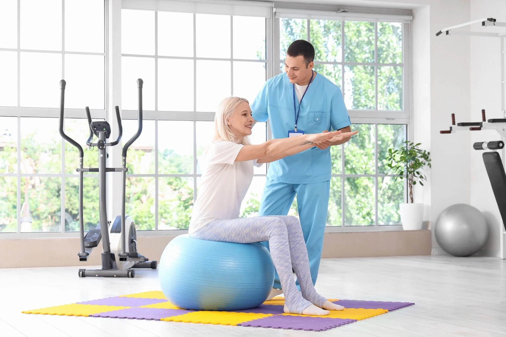 Physical therapist guiding a senior patient through resistance band exercises