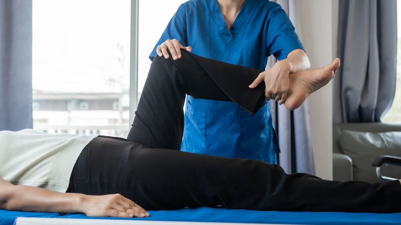 Physical therapist performing knee rehabilitation exercise with a patient