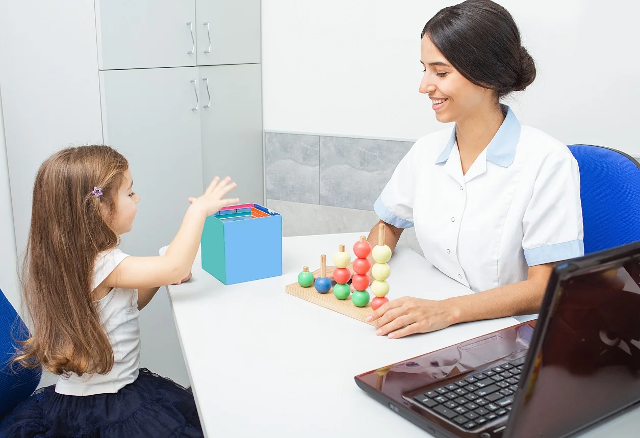 Pediatric occupational therapist working with a child using colorful building blocks