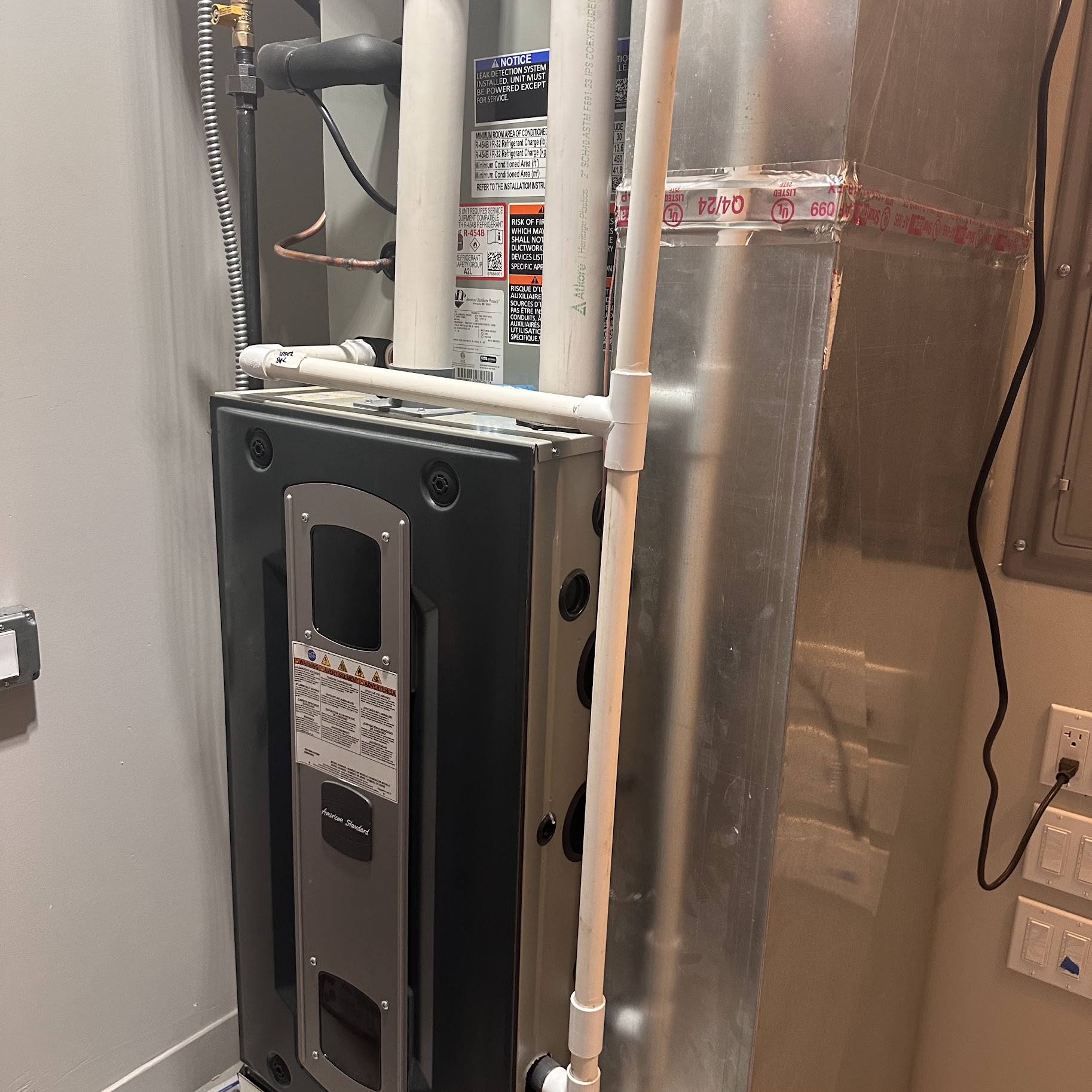 A clean, professionally installed air handler and condensate piping showcase the reliable craftsmanship customers expect from Oasis Heating and Cooling.