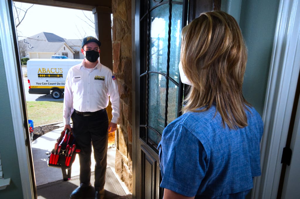 A friendly, punctual technician greets a homeowner at the door, showcasing the reliable service of Abacus Plumbing, Air Conditioning, & Electrical.