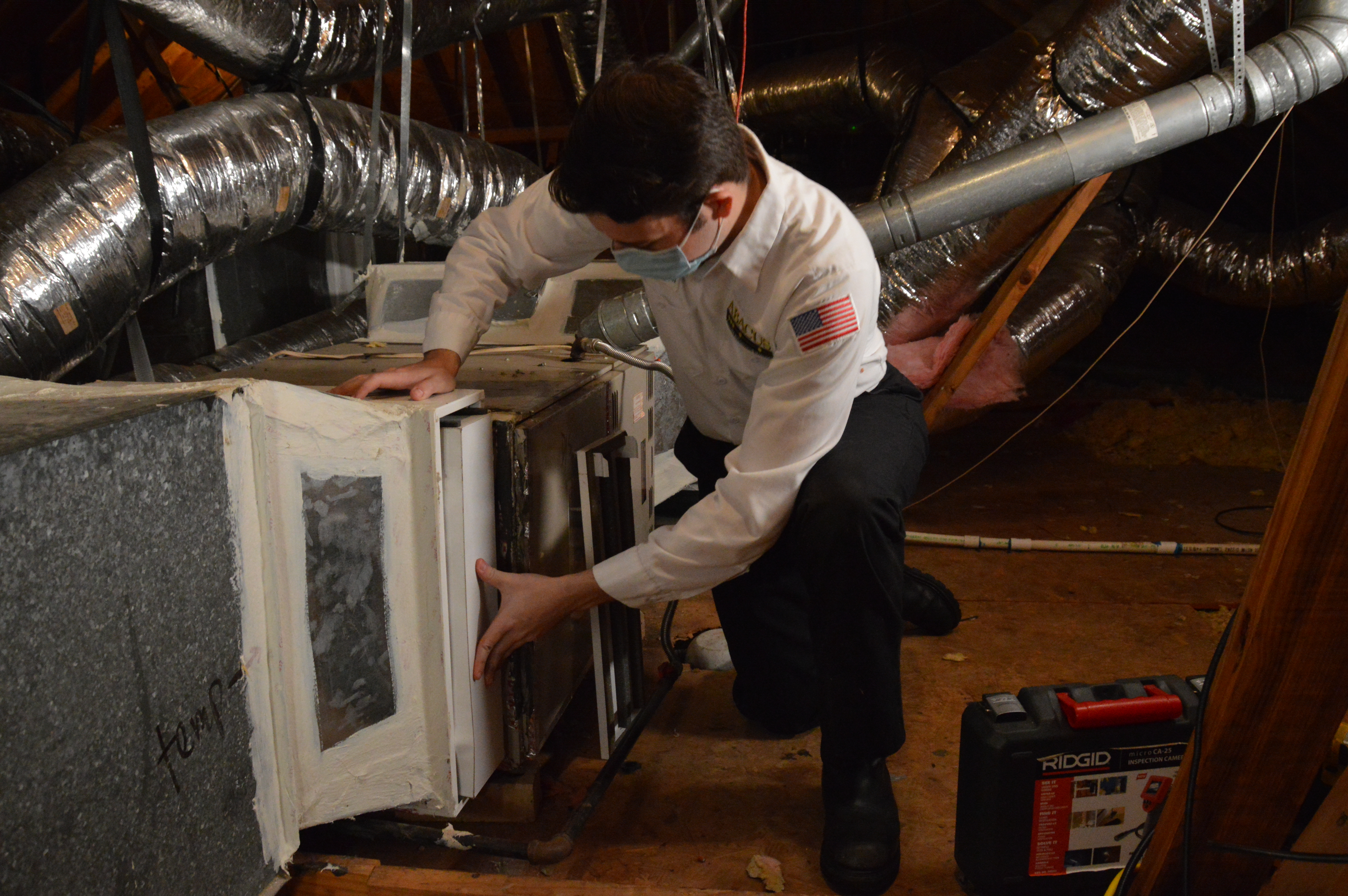 A trained technician from Abacus Plumbing, Air Conditioning, & Electrical demonstrates careful HVAC service in an attic, showcasing dependable craftsmanship.