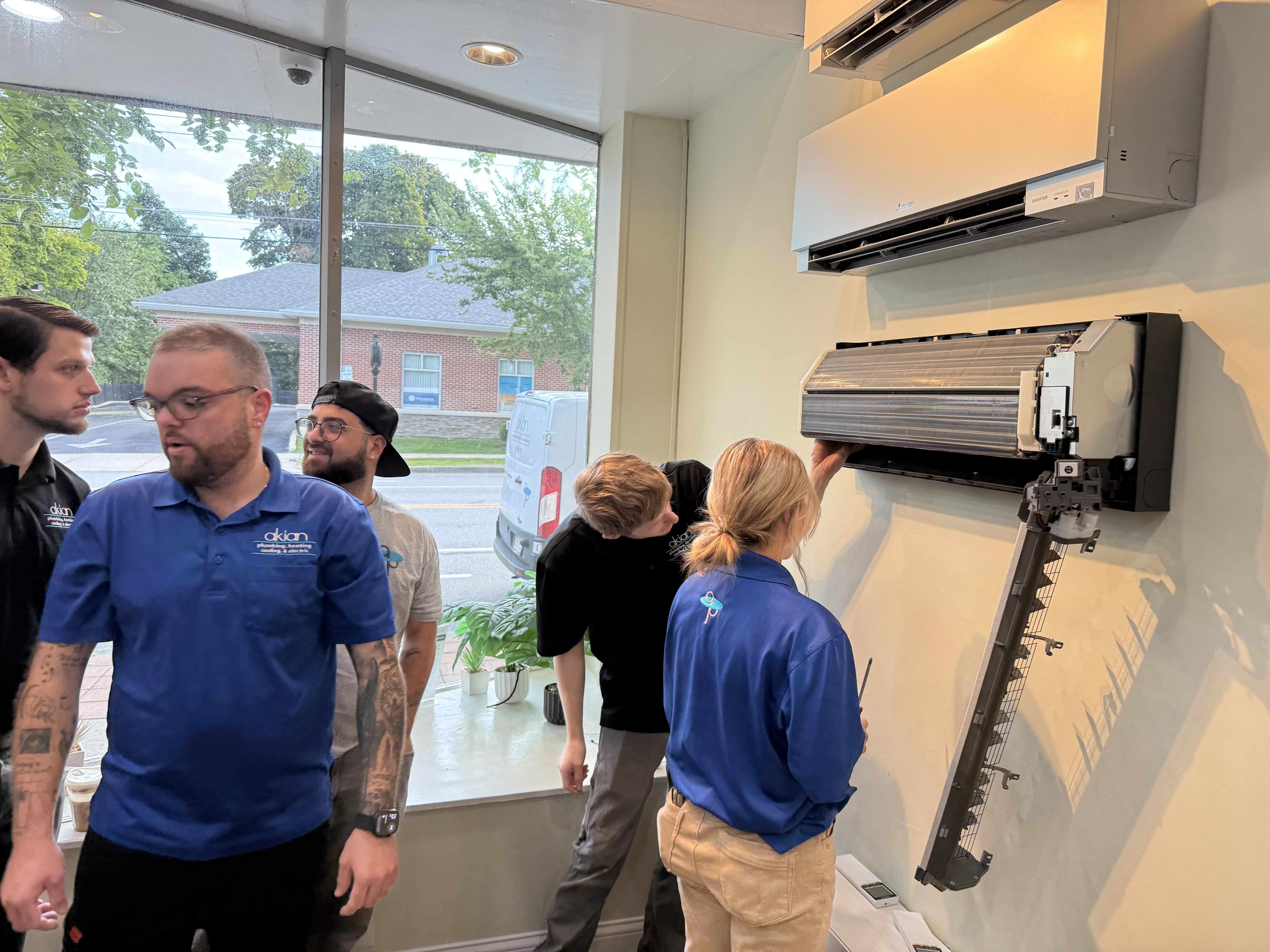 Skilled technicians from Akian Plumbing, Heating, Cooling & Electric demonstrate careful hands-on work during a ductless mini-split service visit.