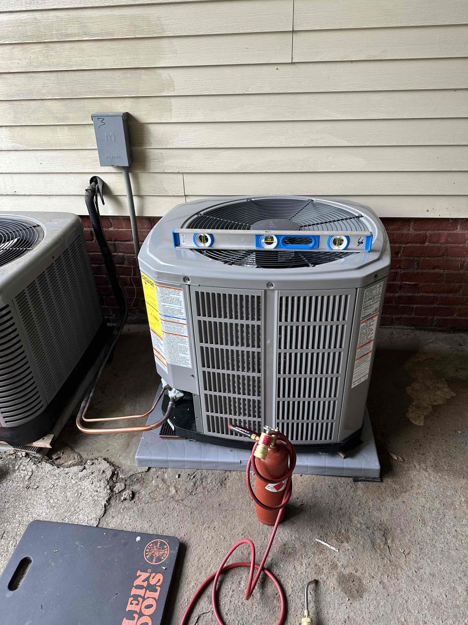 Akian Plumbing, Heating, Cooling & Electric ensures precise installations and reliable performance, demonstrated here during a careful condenser leveling and service.