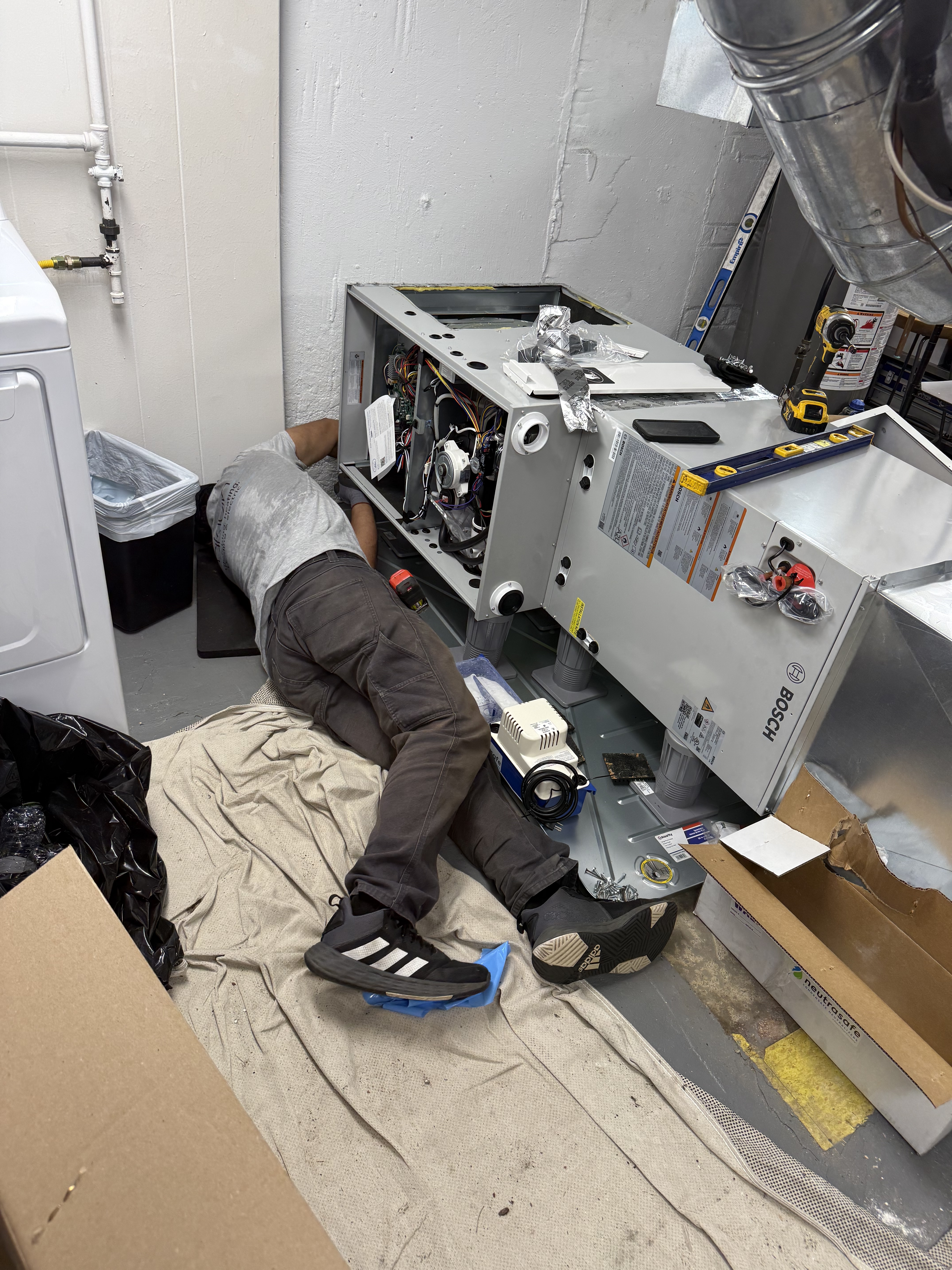 A skilled technician from Akian Plumbing, Heating, Cooling & Electric carefully services an indoor HVAC unit, showing meticulous craftsmanship and respect for your space.