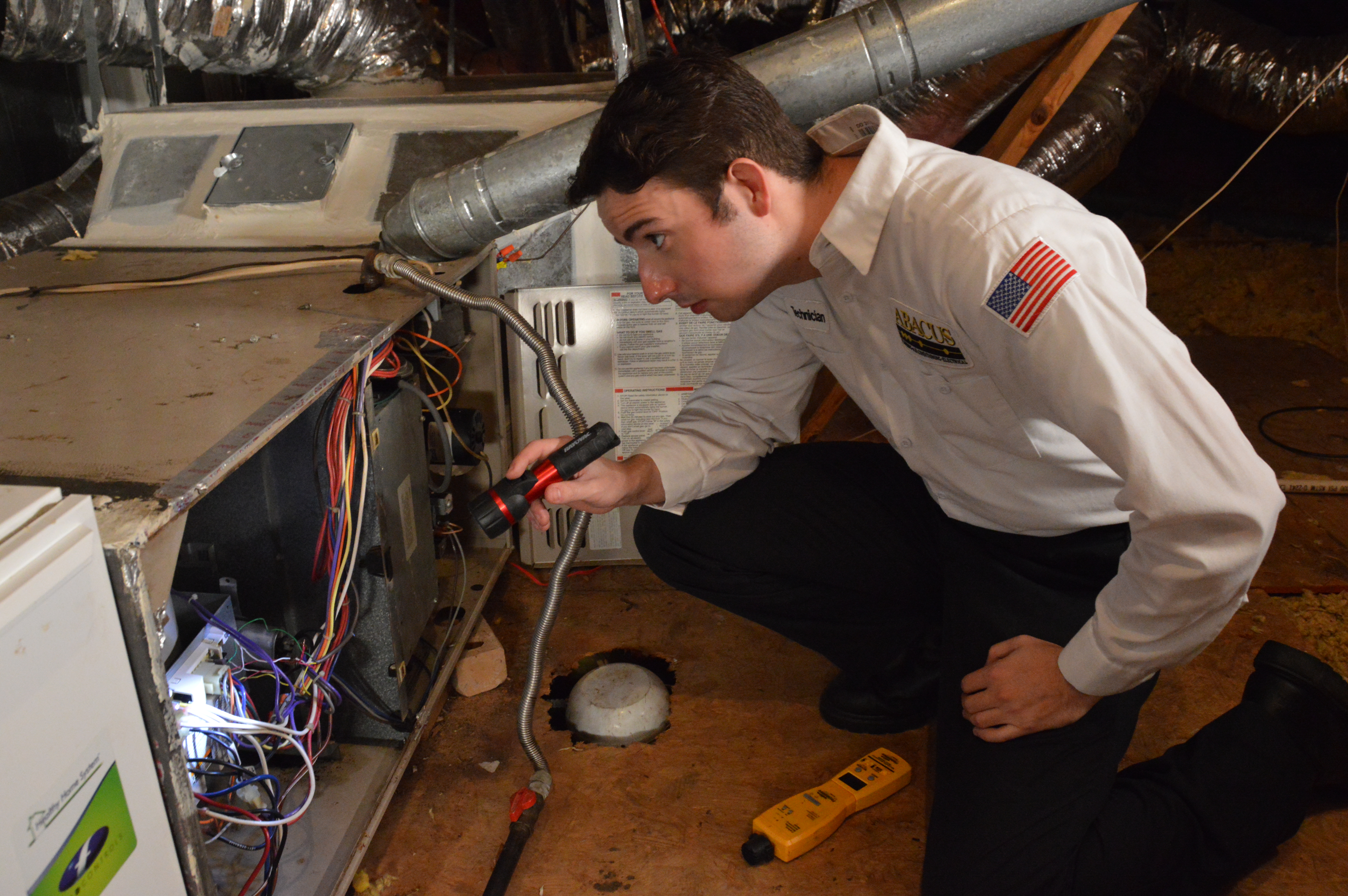 A trained Abacus Plumbing, Air Conditioning, & Electrical technician inspects an attic air handler carefully to ensure reliable, safe system performance.