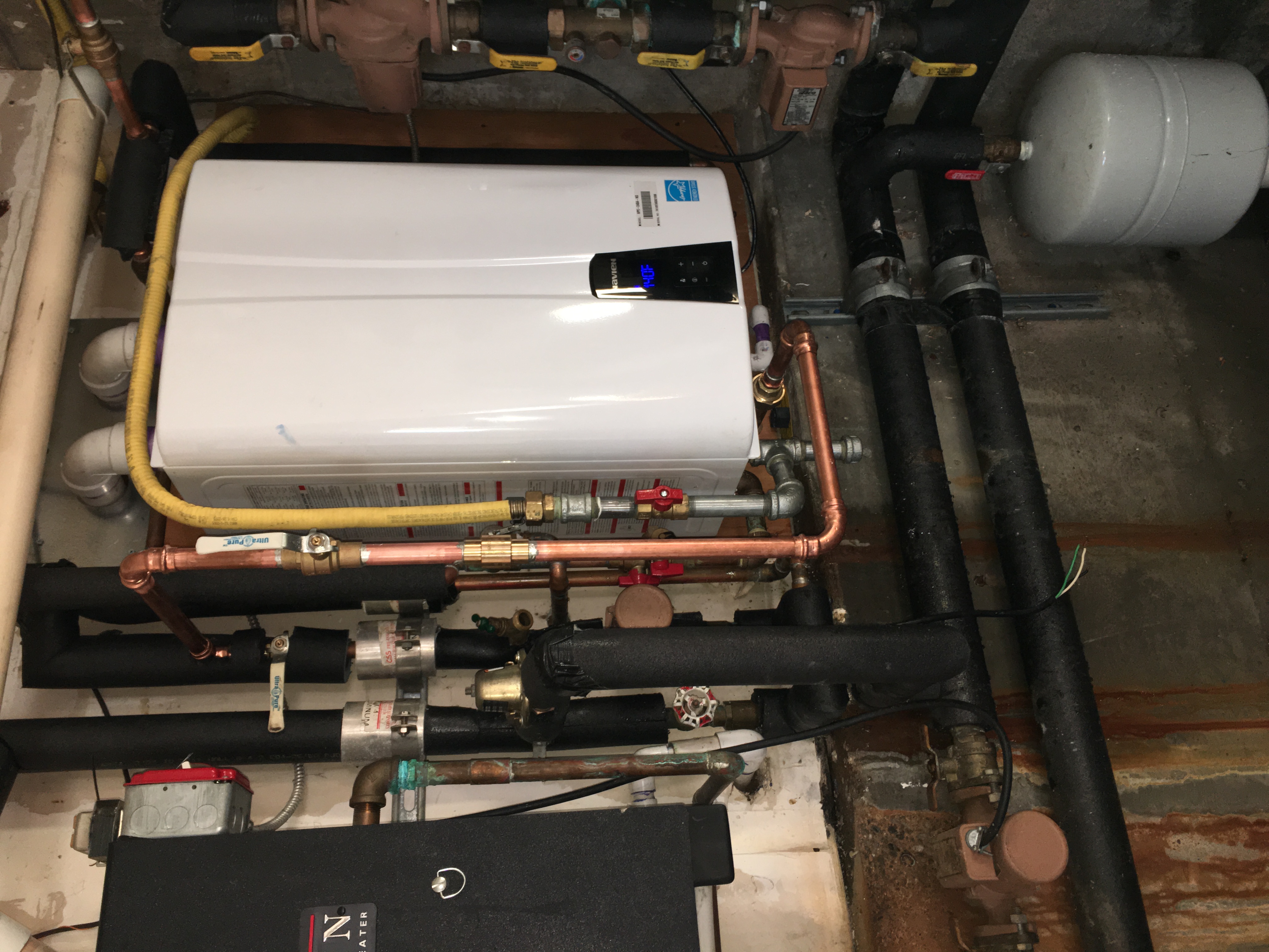 Cleanly installed tankless boiler with organized copper piping highlights the reliable craftsmanship customers expect from Magic Plumbing Heating & Cooling.