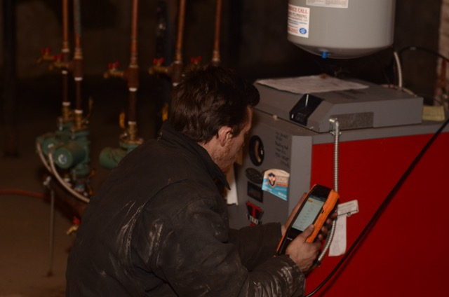 A skilled technician from Lloyd Plumbing, Heating, Air, Electrical inspects a boiler with precise diagnostic testing to ensure reliable home heating.