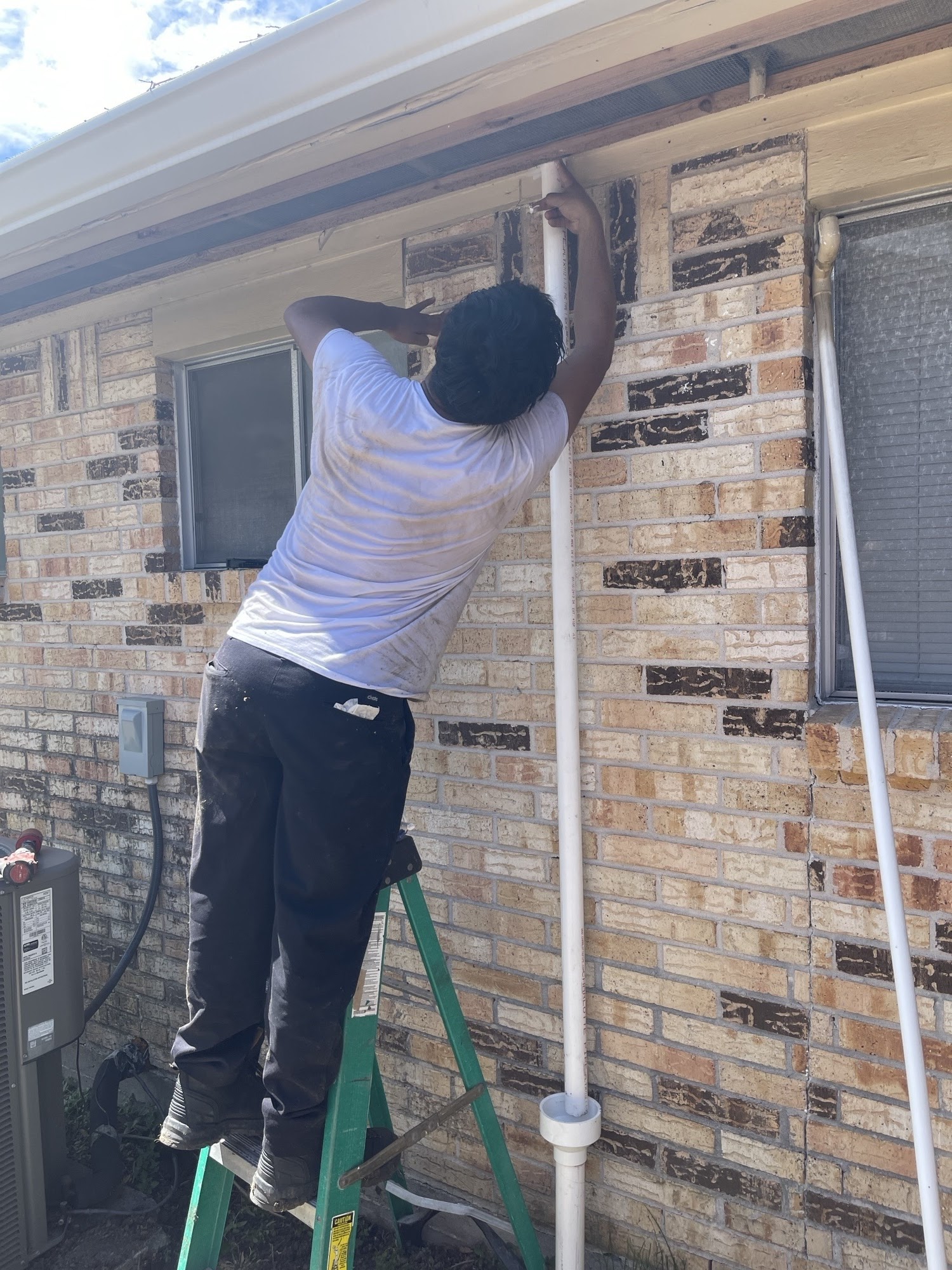 A skilled technician from Abacus Plumbing, Air Conditioning & Electrical fixes exterior piping on-site, showing dependable craftsmanship and care.
