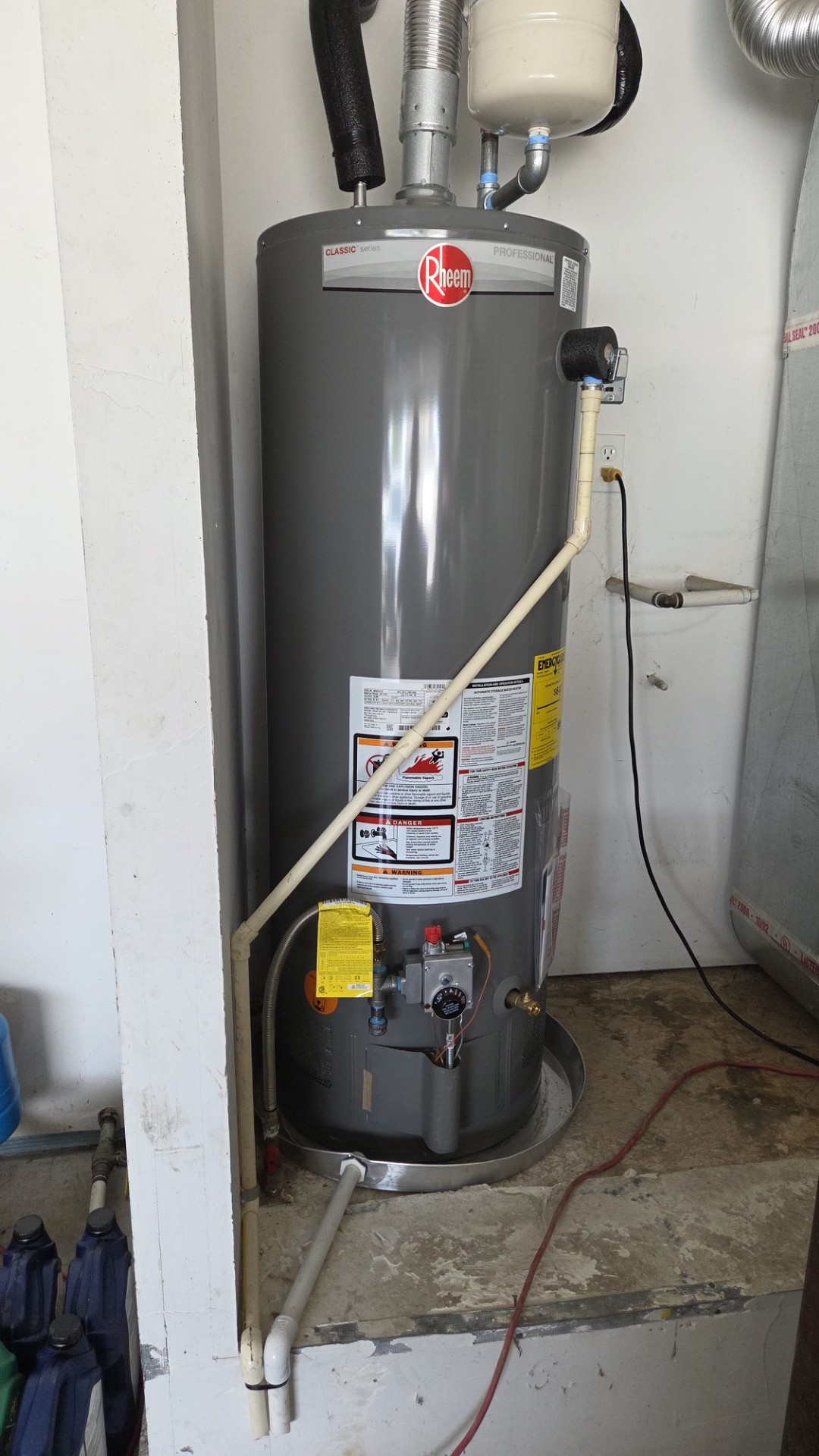 A clean, professionally installed Rheem water heater demonstrates durable craftsmanship and reliable performance from Home Heating & Air Conditioning.