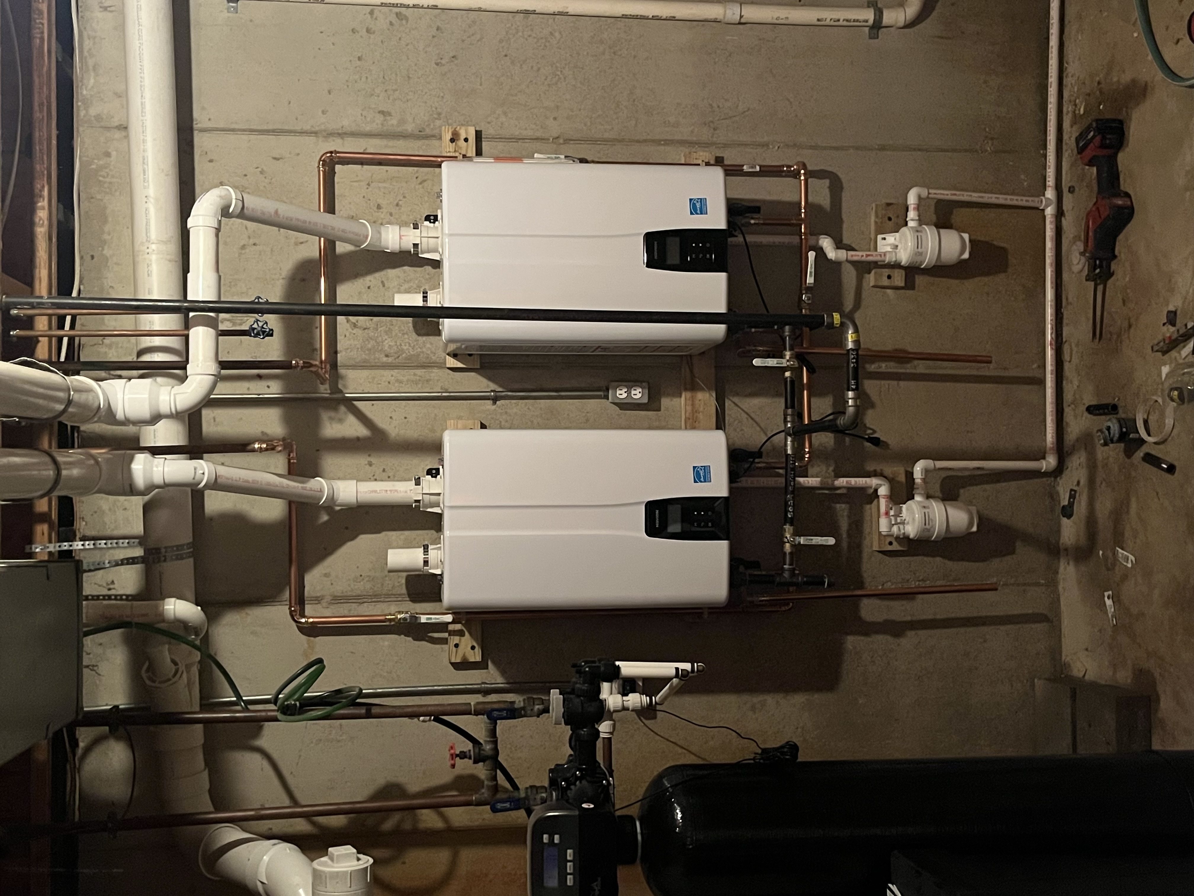 Clear, professional tankless water heater installation in a finished basement shows Summers Plumbing Heating & Cooling delivering reliable hot water performance.