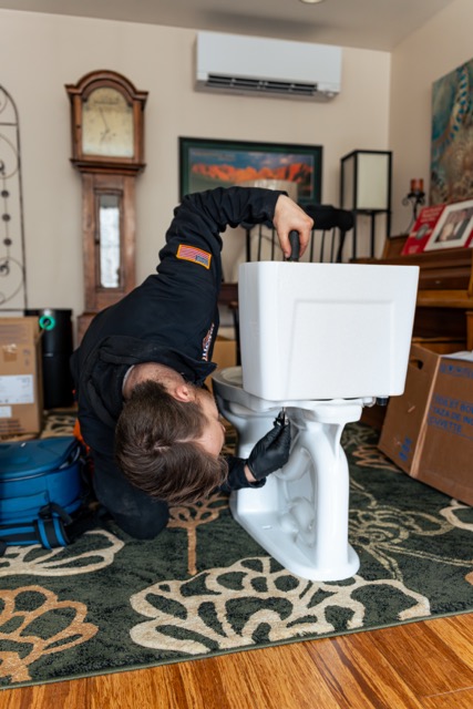 Our technicians deliver careful, professional in-home installations and repairs, as shown by Lloyd Plumbing, Heating, Air, Electrical handling a toilet with precision.