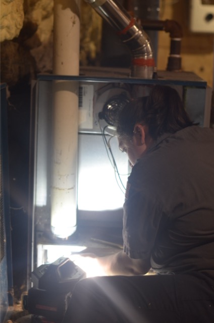 A skilled technician from Lloyd Plumbing, Heating, Air, Electrical carefully inspects a home furnace to ensure reliable, safe heating.