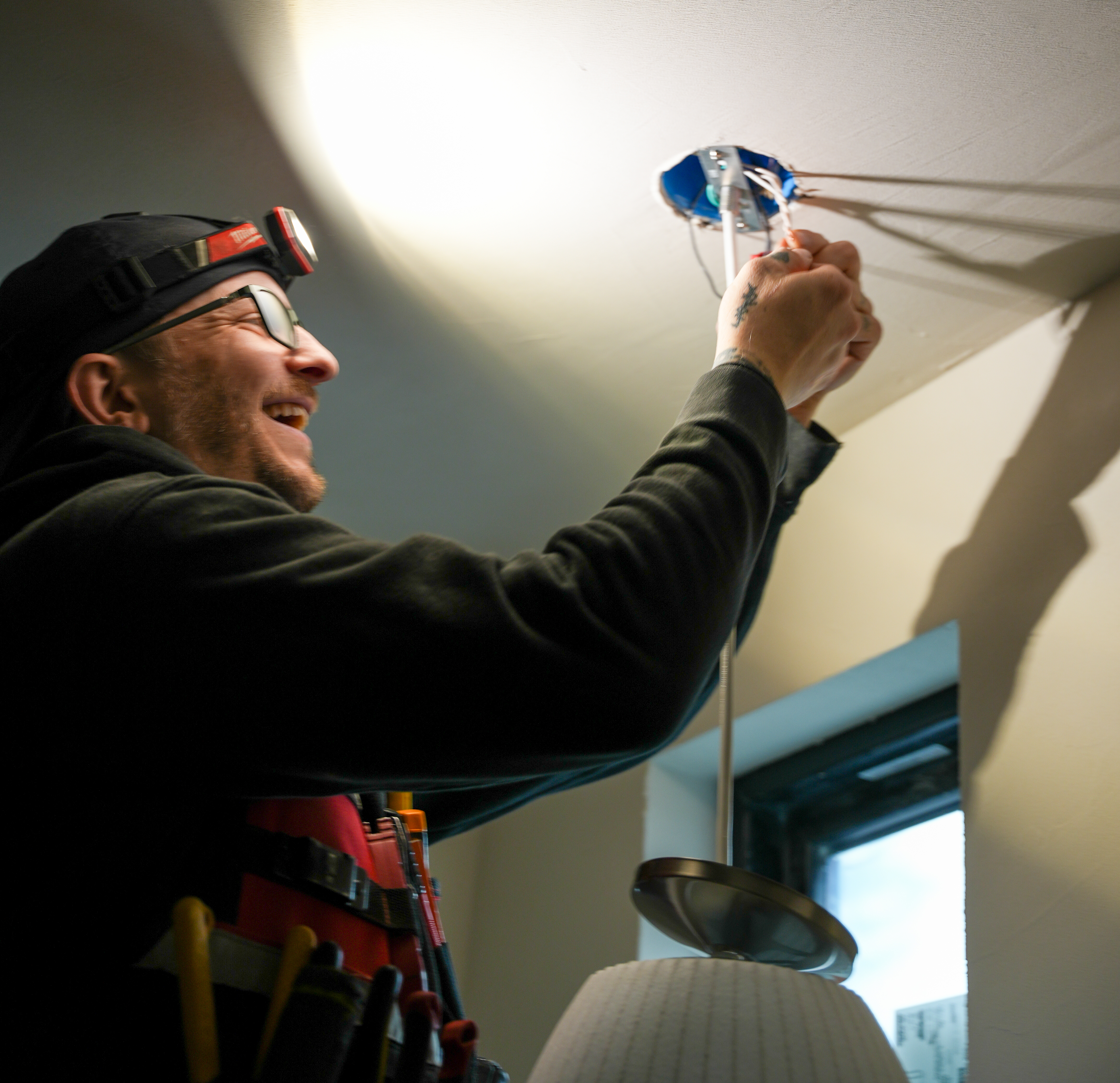 A skilled technician from Eco Electric, Plumbing, Heating and Air carefully installs a ceiling light, showcasing reliable craftsmanship and care.