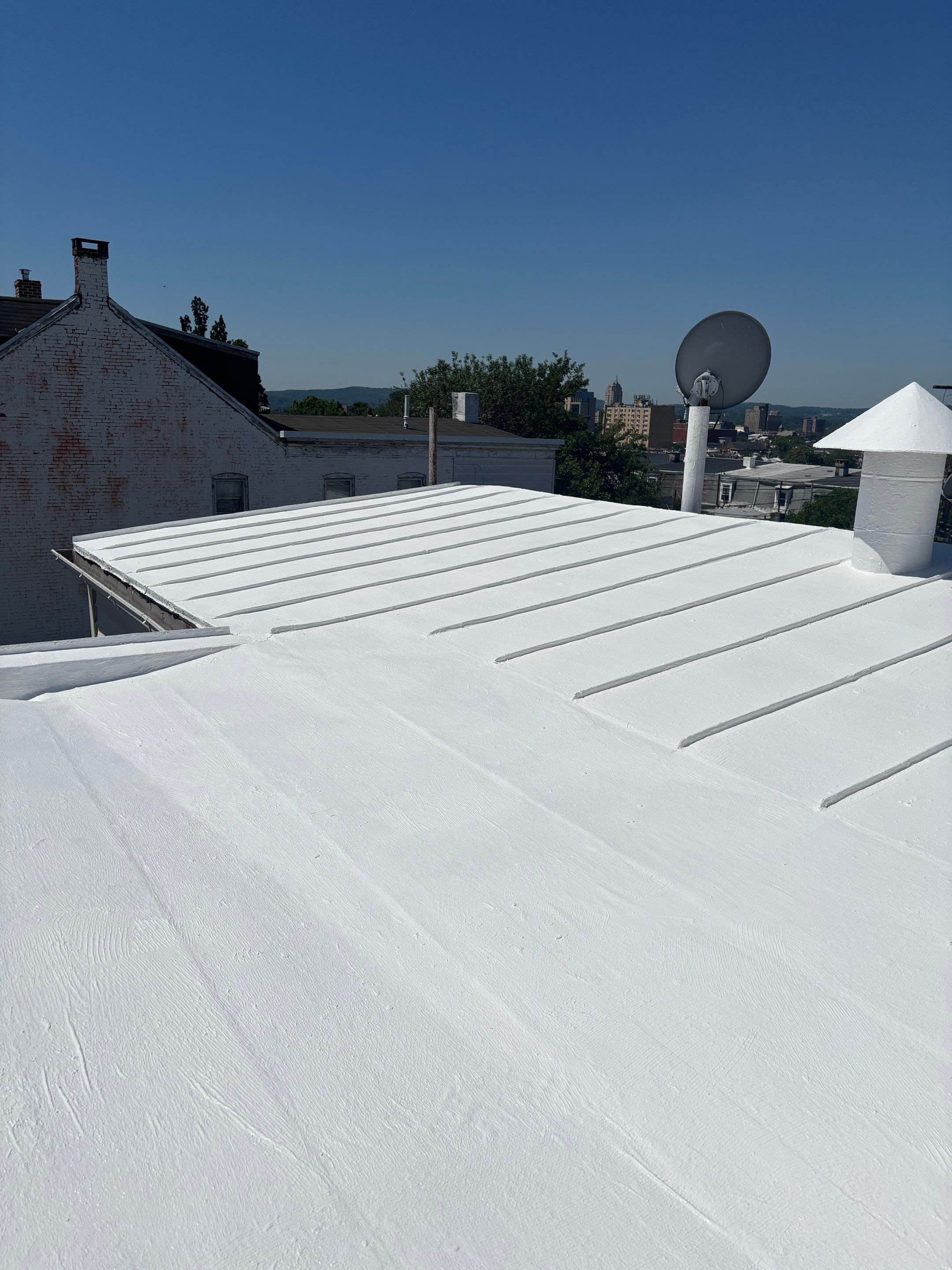 Bright reflective coating shows Mast Roofing & Construction's craftsmanship and durability, protecting this rooftop while improving energy reflectivity.