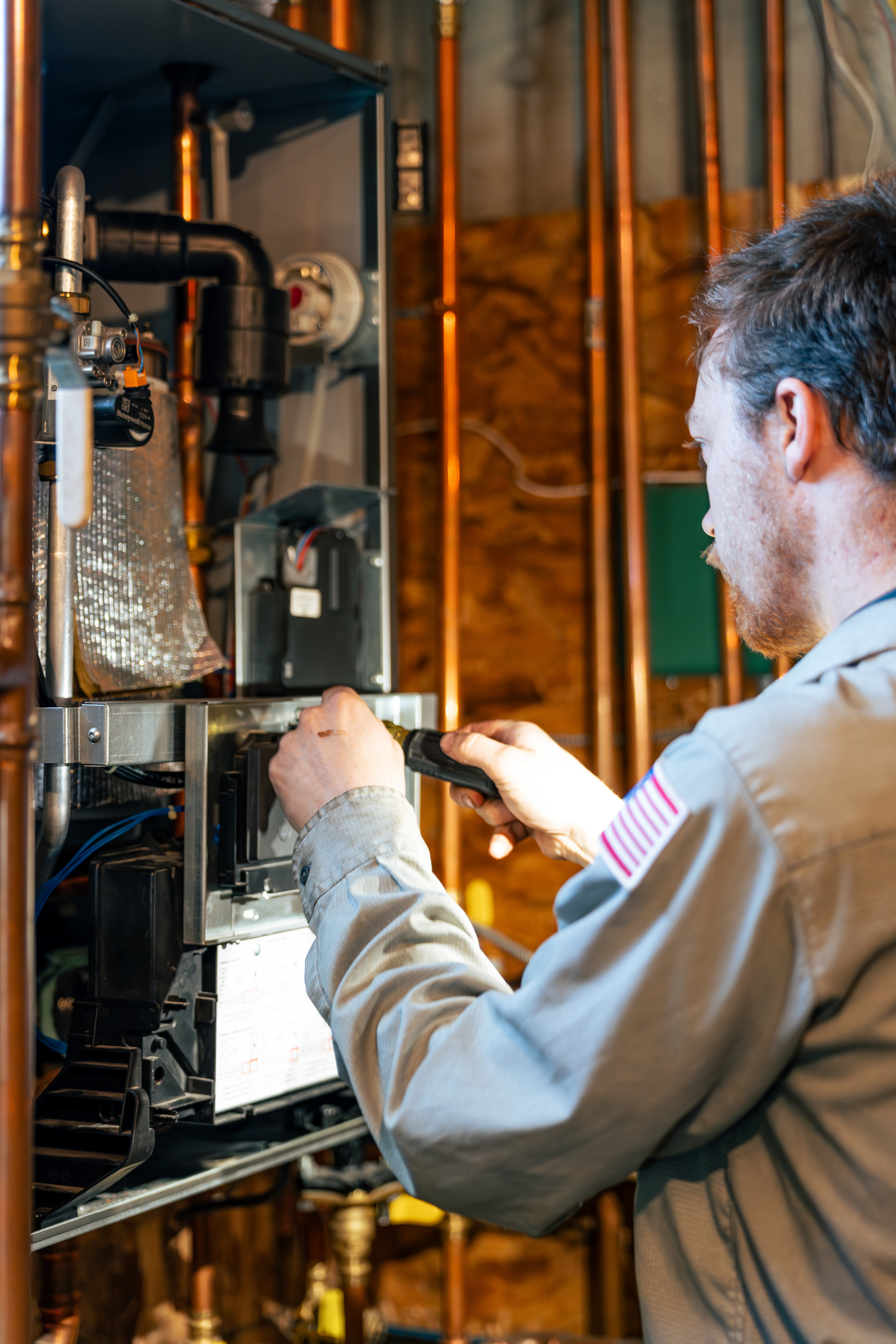 A skilled technician from Lloyd Plumbing, Heating, Air, Electrical demonstrates careful on-site workmanship to keep your heating system running safely and reliably.