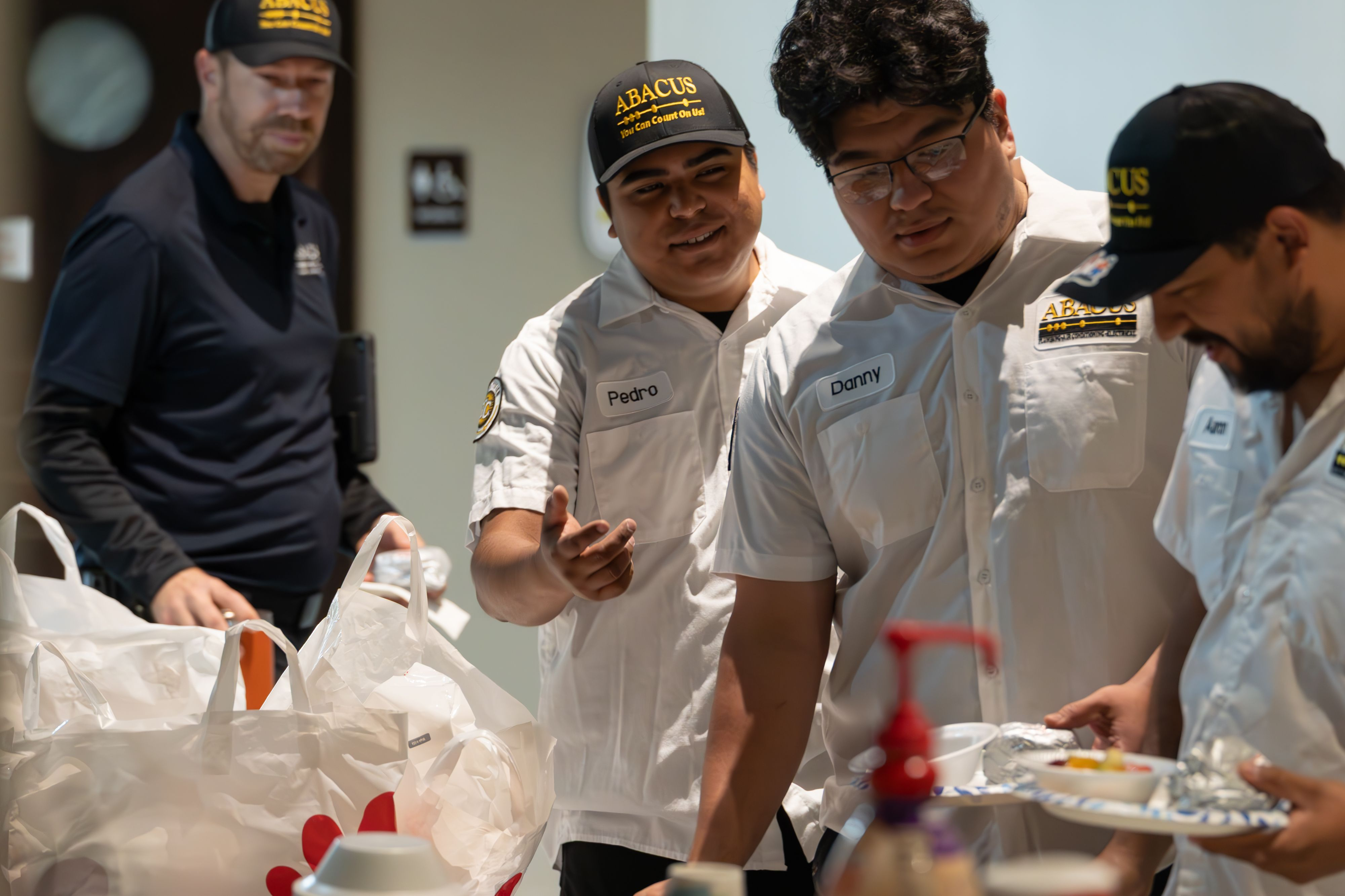 Abacus Plumbing, Air Conditioning, & Electrical showcases a friendly, professional team sharing a quick meal together, highlighting dependable service and strong teamwork.