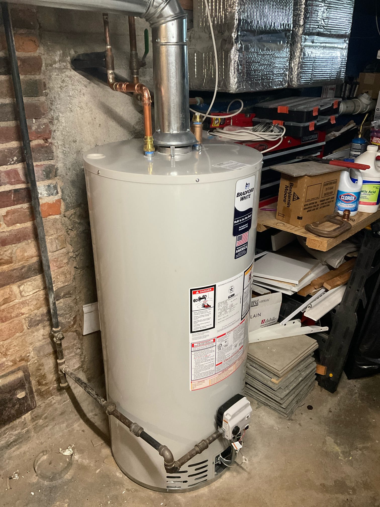 Reliable craftsmanship in a tight basement space, Akian Plumbing, Heating, Cooling & Electric installed this Bradford White water heater with clean piping and secure venting.