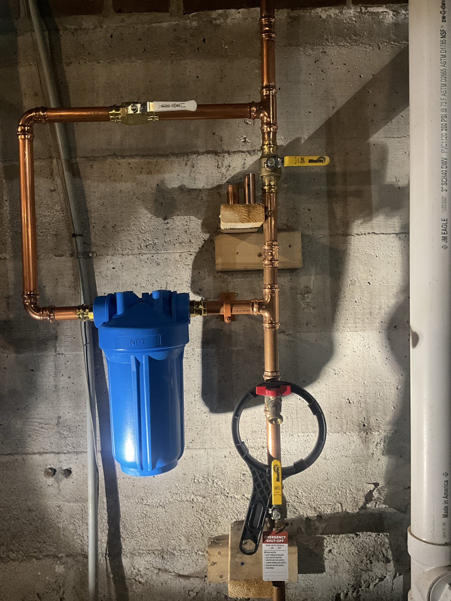 Clean, professional copper plumbing with a water filter and labeled emergency shut-off shows Akian Plumbing, Heating, Cooling & Electric's reliable craftsmanship and safety focus.
