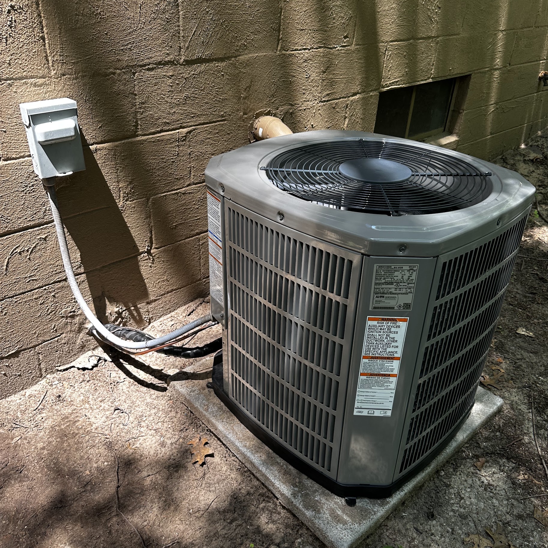 A clean, professionally installed outdoor AC condenser on a sturdy pad shows Oasis Heating and Cooling's commitment to durable, reliable comfort.