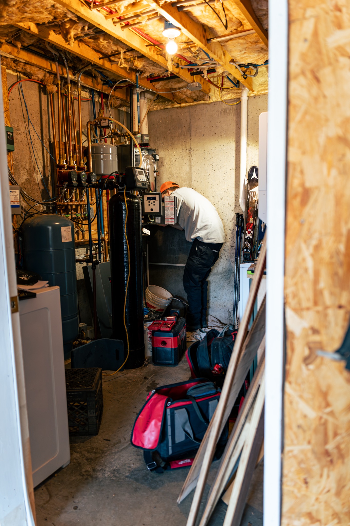 A Lloyd Plumbing, Heating, Air, Electrical technician performs precise basement system work, showcasing skilled, reliable service and attention to detail.