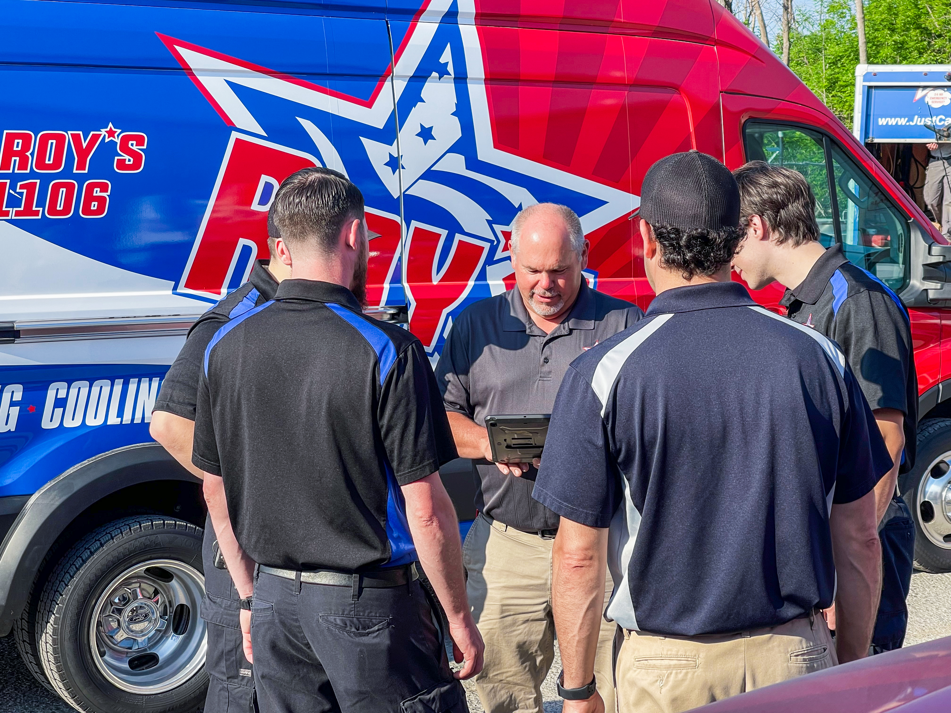 Roy's Plumbing, Heating, Cooling & Electrical showcases its professional team and branded service van, ready to serve with modern solutions.