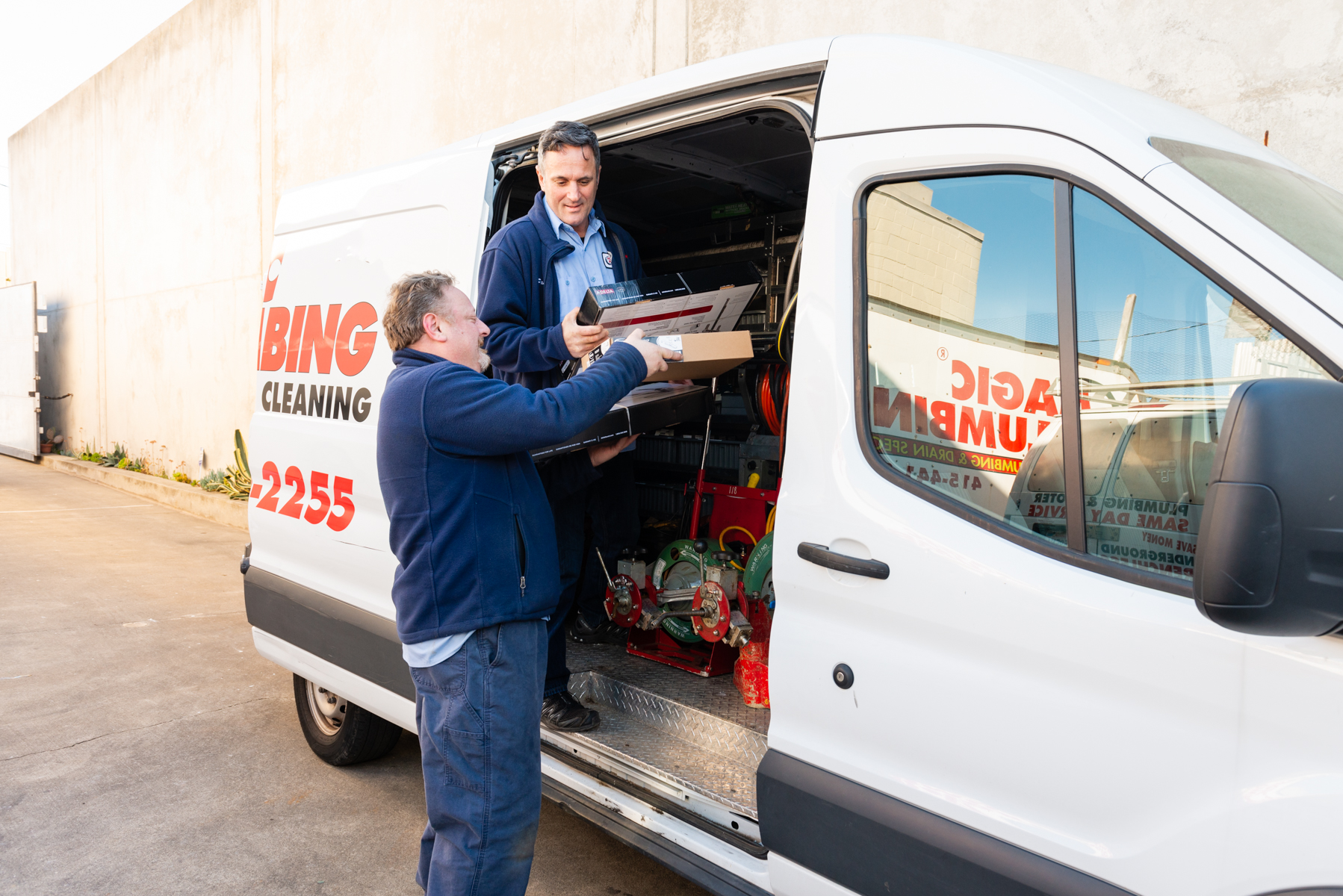 Friendly technicians from Magic Plumbing Heating & Cooling load equipment into their van, showing dependable service and clear professionalism.