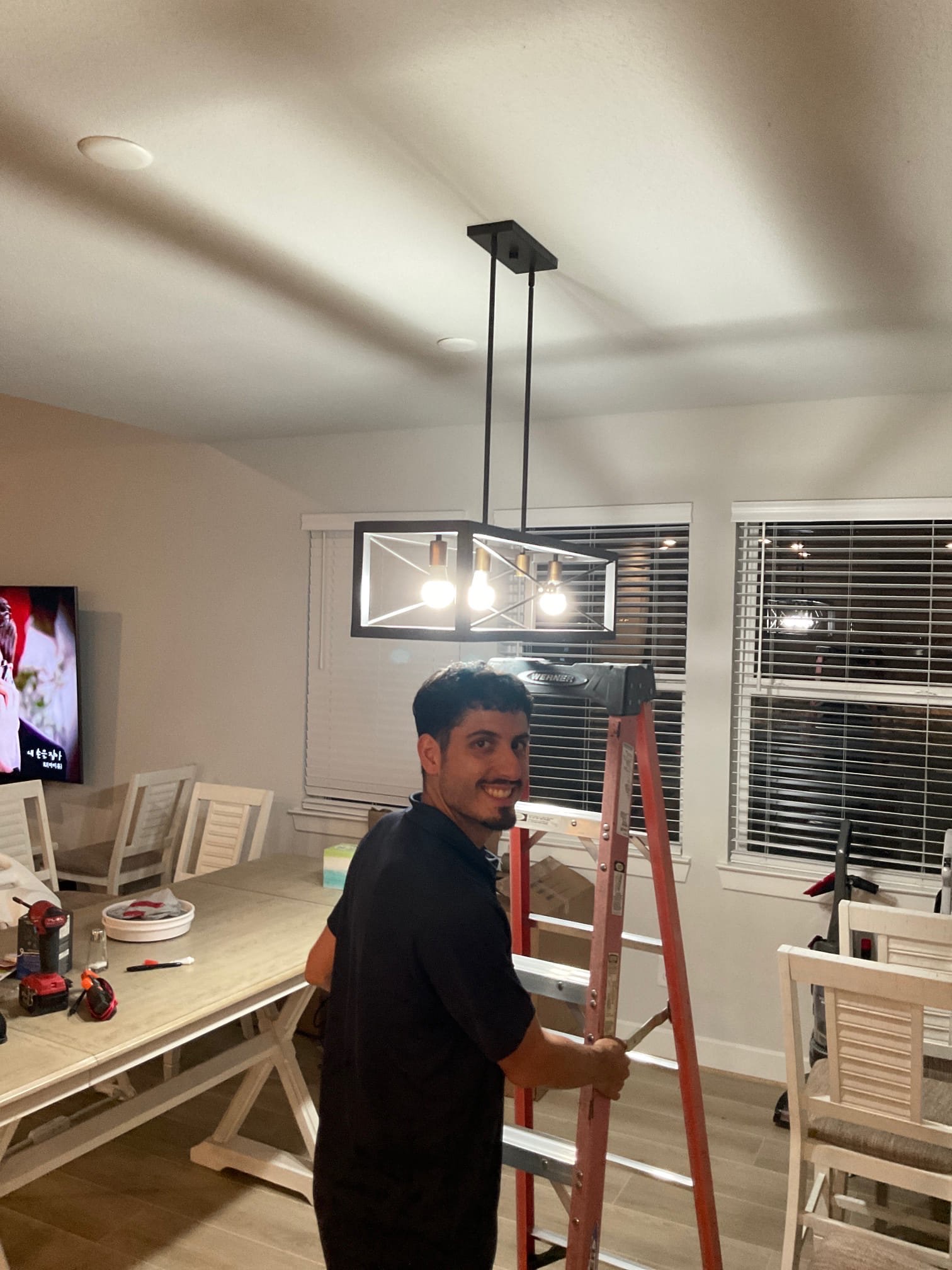 A friendly West Houston Electric, Inc. technician finishes a clean, professional lighting installation that enhances this dining space.
