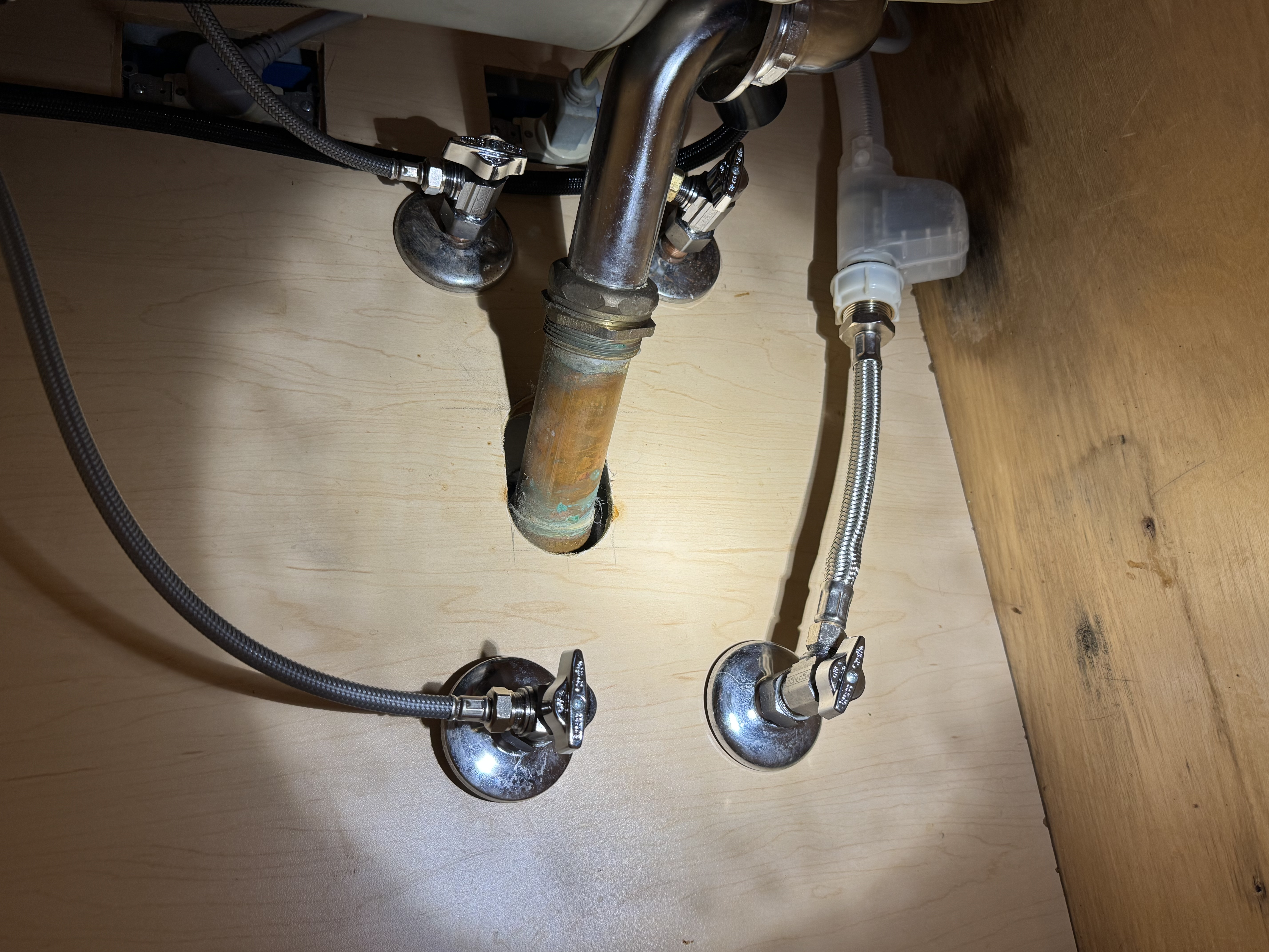 Cleanly installed shutoff valves and supply lines under a sink show the careful workmanship customers trust from Big Island Plumbing.