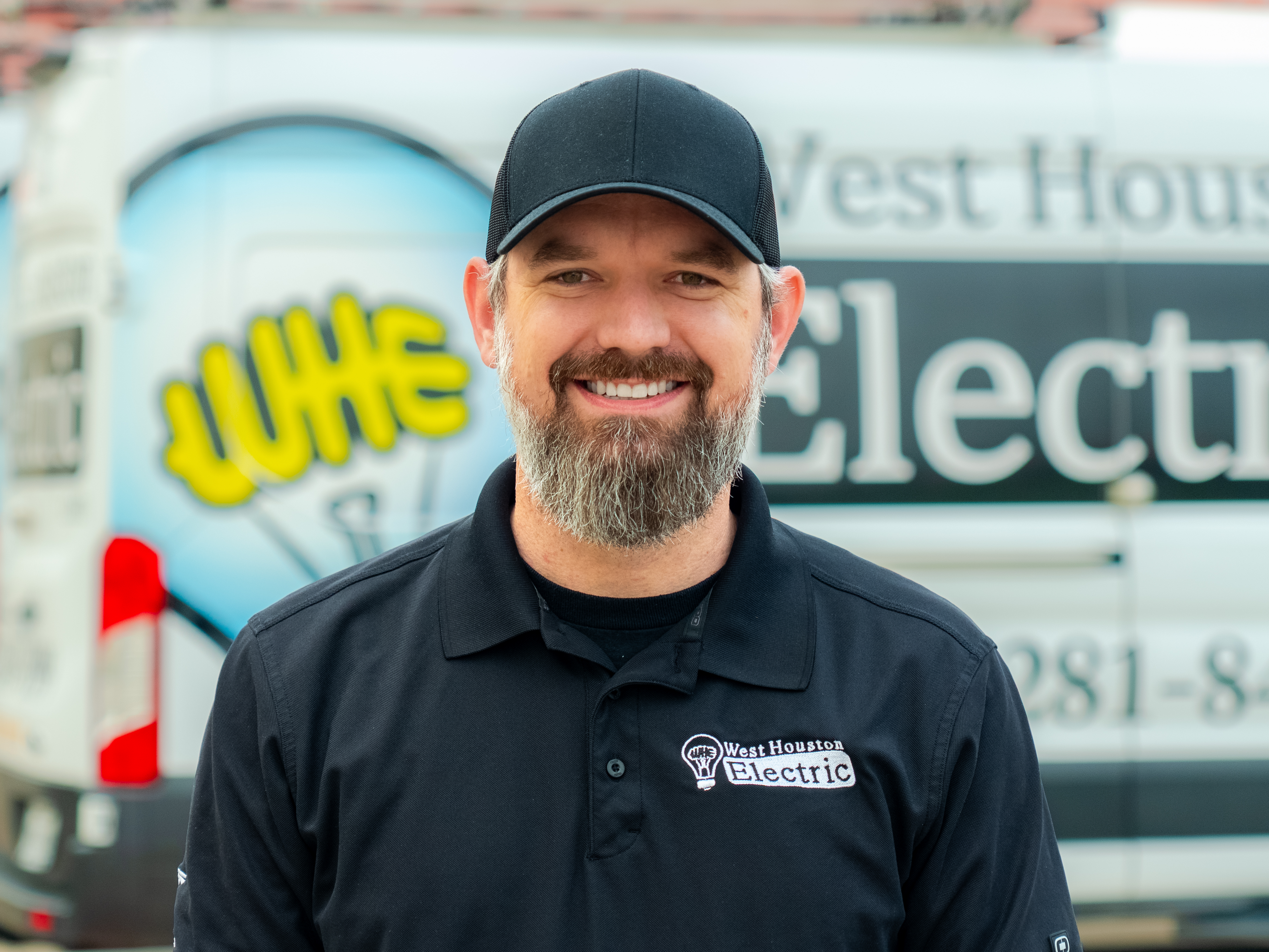 A friendly, professional technician from West Houston Electric, Inc. greets customers with a confident smile and clear company branding.