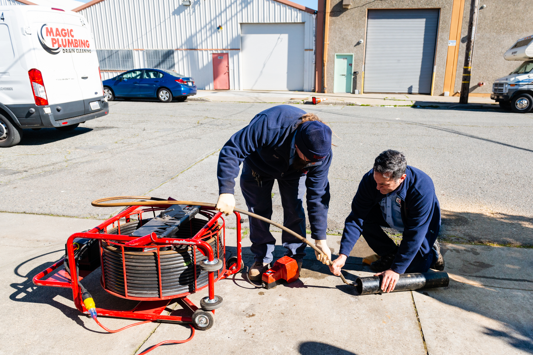 Confident technicians from Magic Plumbing Heating & Cooling demonstrate reliable drain-cleaning service with visible care and teamwork on-site.
