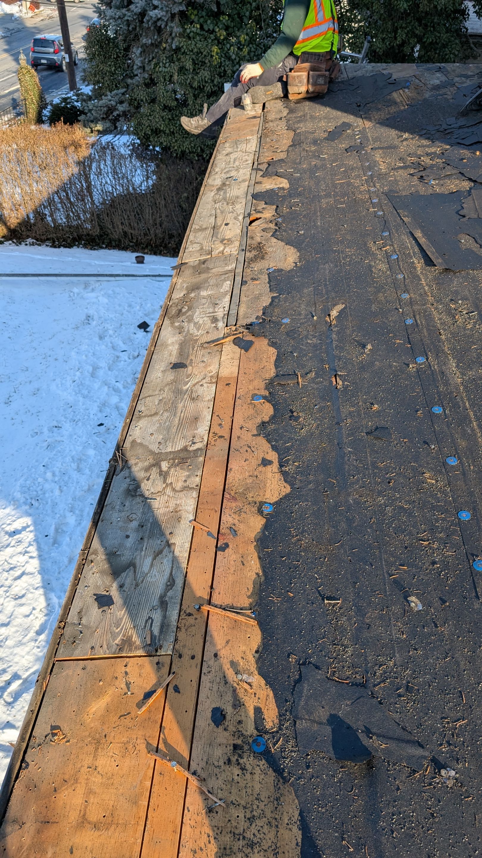 Trusted craftsmanship on a winter re-roof shows Mosaic Roofing & Exteriors restoring damaged decking and preparing a durable new roof.