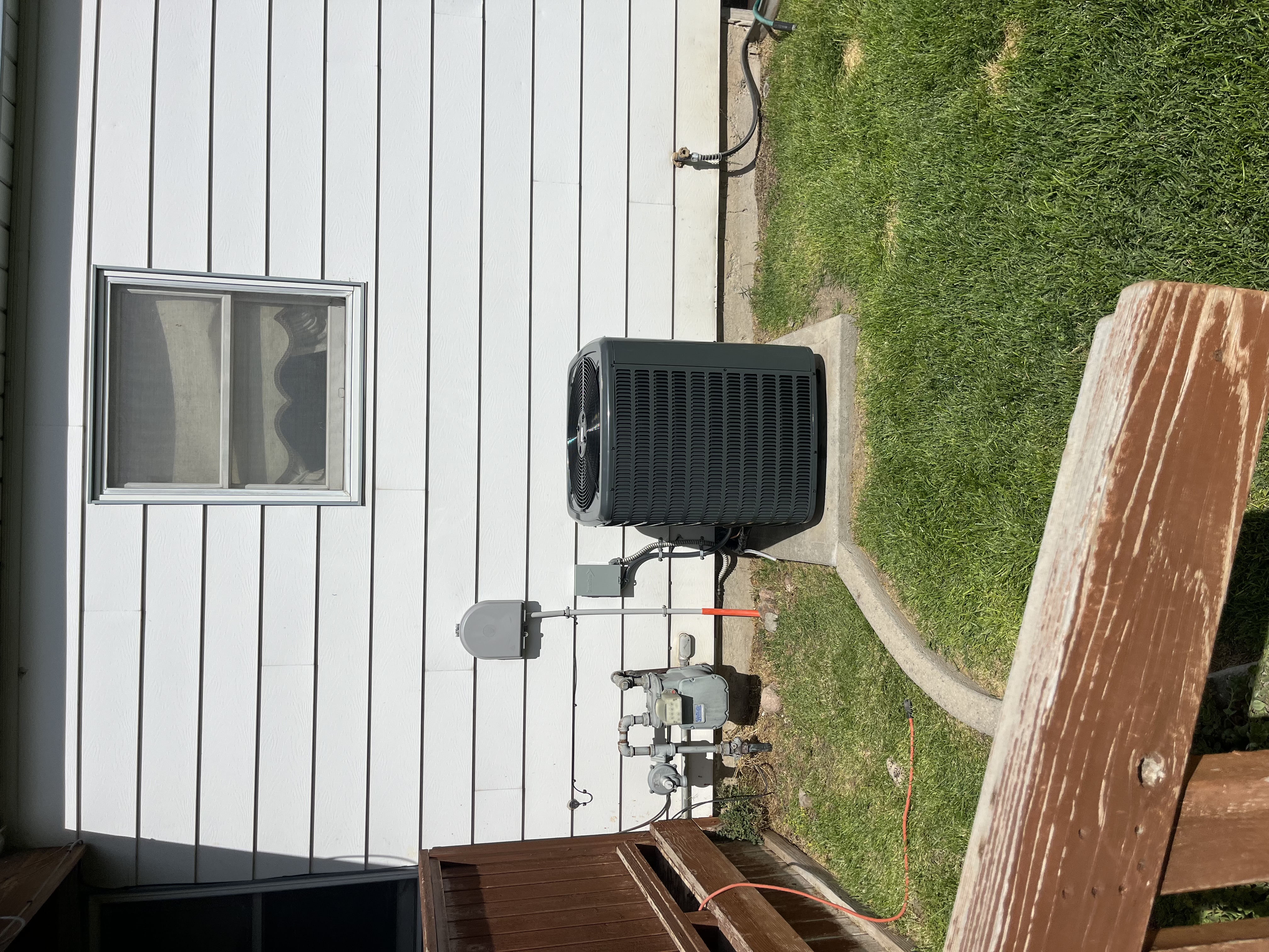 A professionally installed outdoor AC unit on a tidy home exterior showcases reliability and care from Home Heating & Air Conditioning.