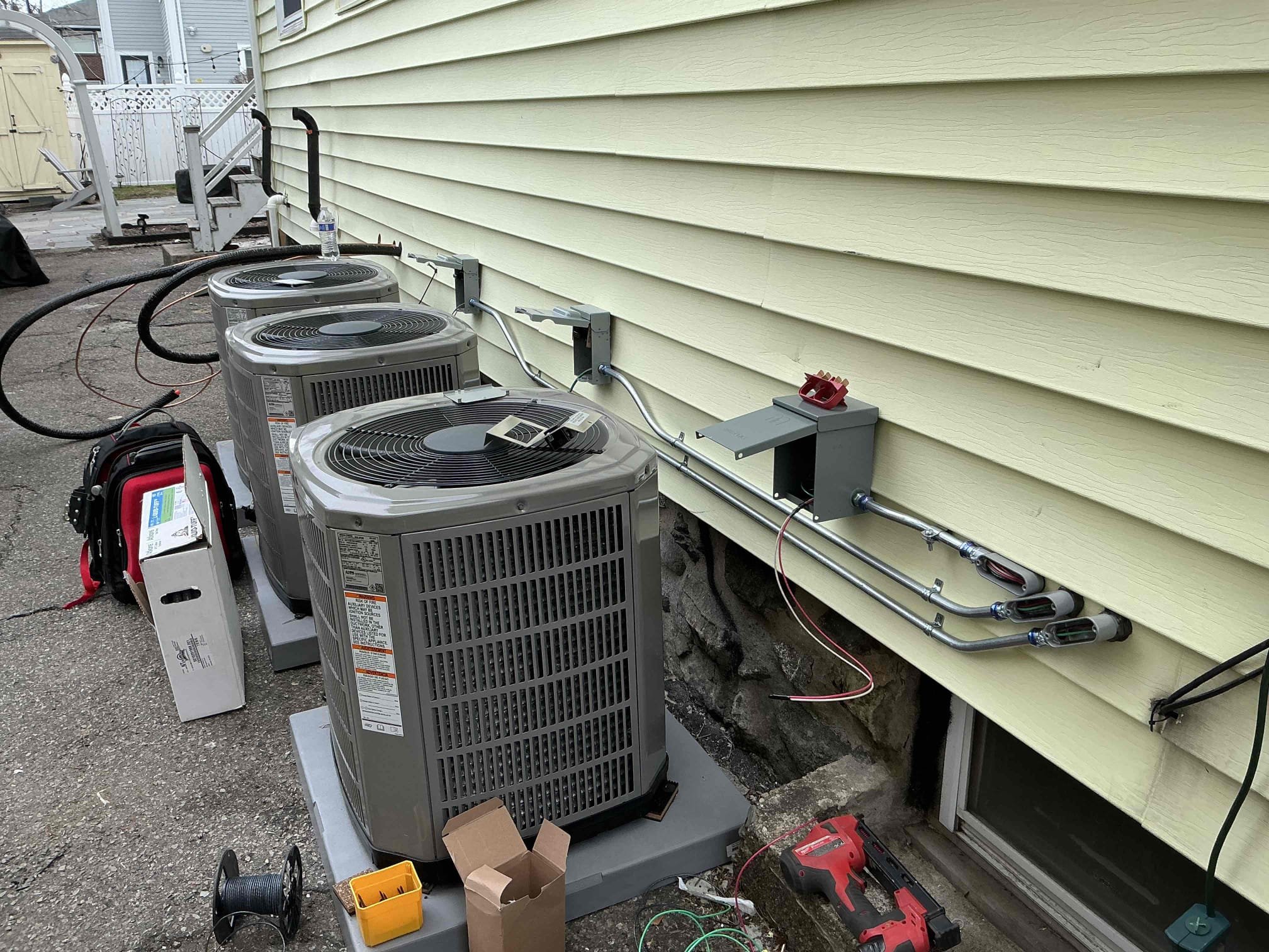 Professional multi-unit HVAC installation with tidy conduit and disconnects highlights Akian Plumbing, Heating, Cooling & Electric's reliable craftsmanship and attention to detail.