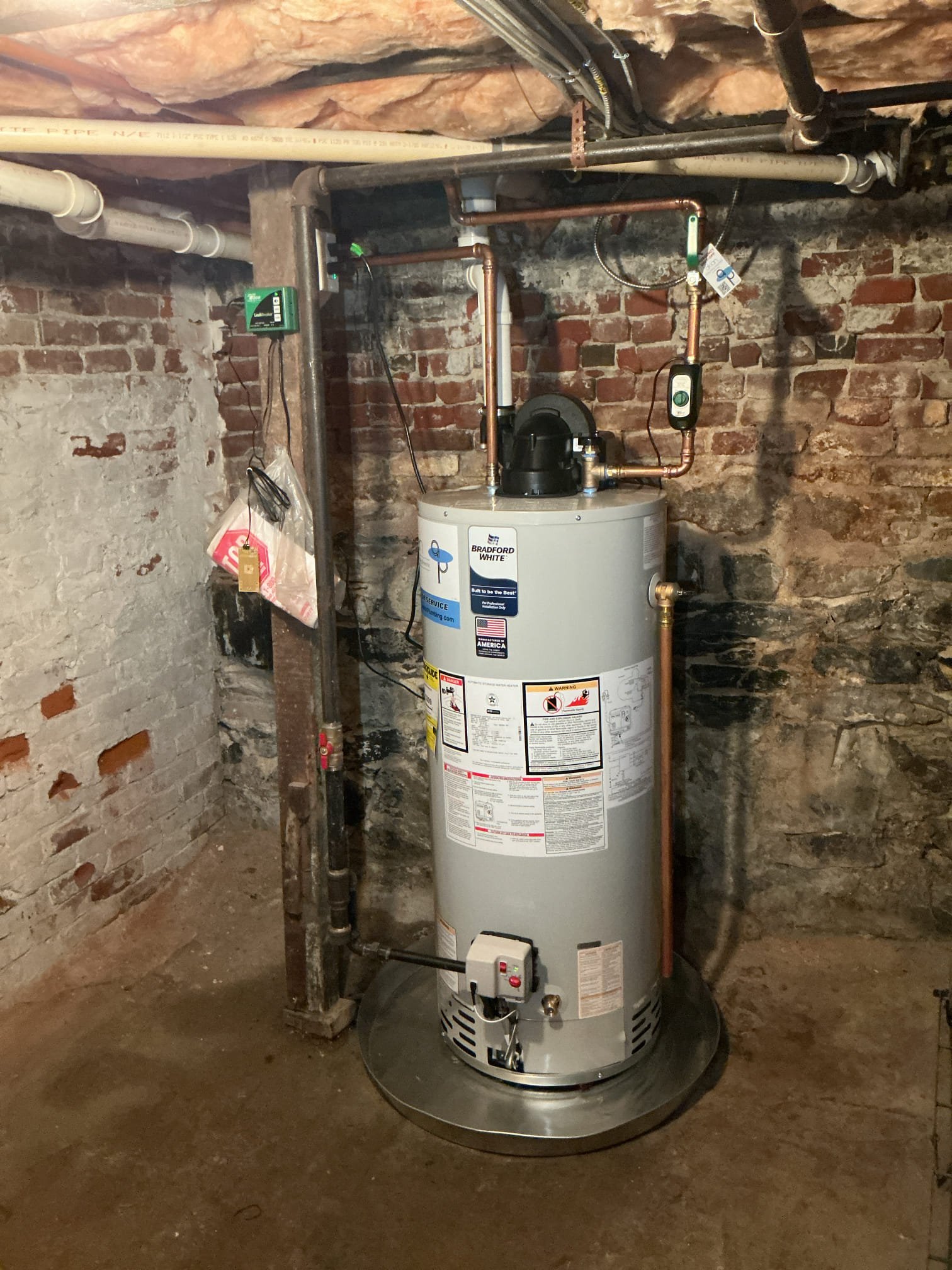 A reliable Bradford White water heater professionally installed in an unfinished basement shows the dependable craftsmanship customers expect from Akian Plumbing, Heating, Cooling & Electric.