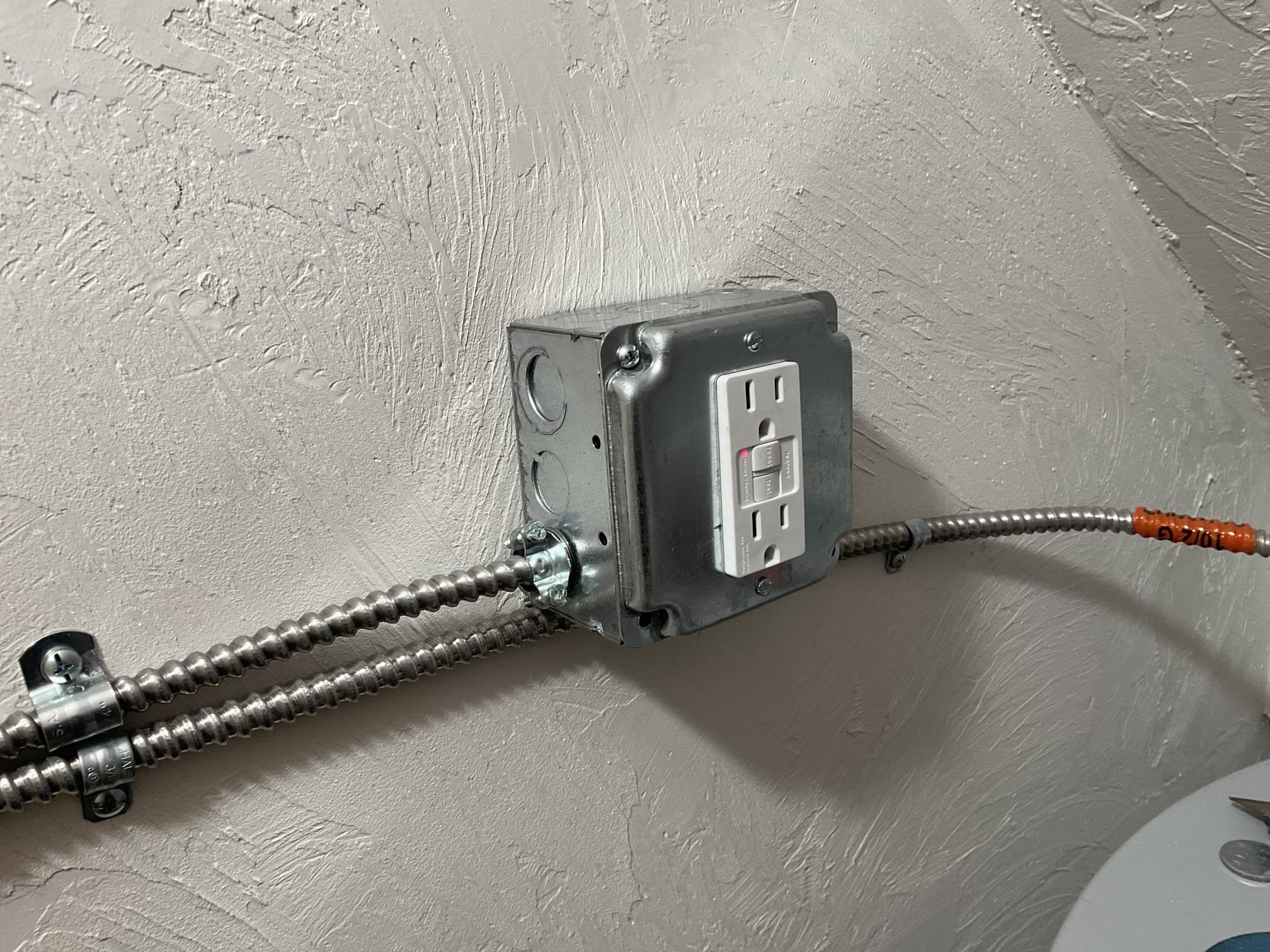 Akian Plumbing, Heating, Cooling & Electric demonstrates reliable, code-focused electrical work with tidy conduit runs and a protected GFCI outlet.