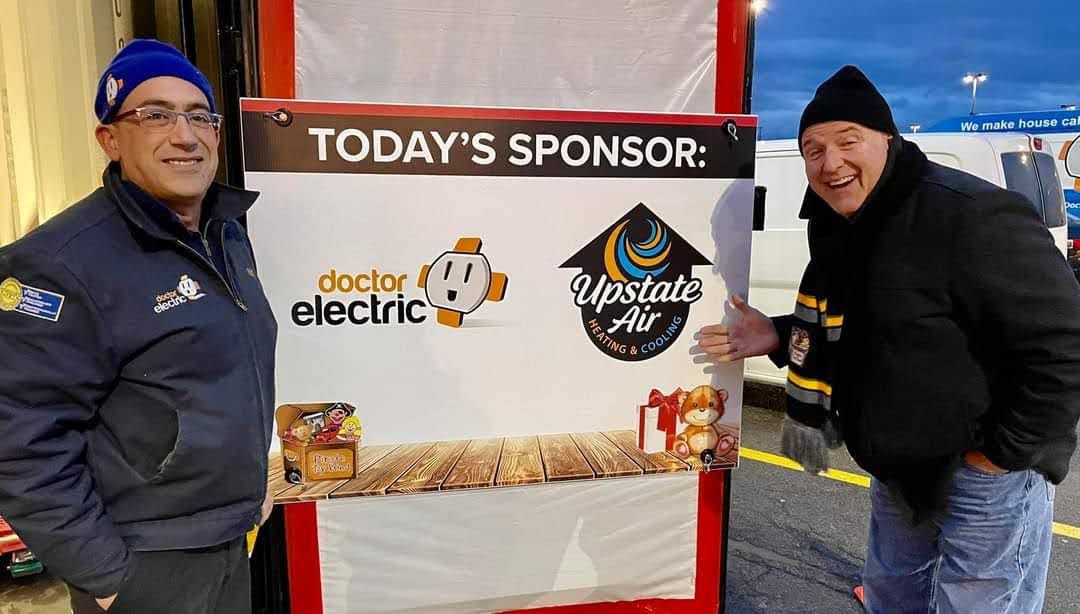 Smiling team members showcase Doctor Electric’s community sponsorship with friendly service and trusted branding at an outdoor event.