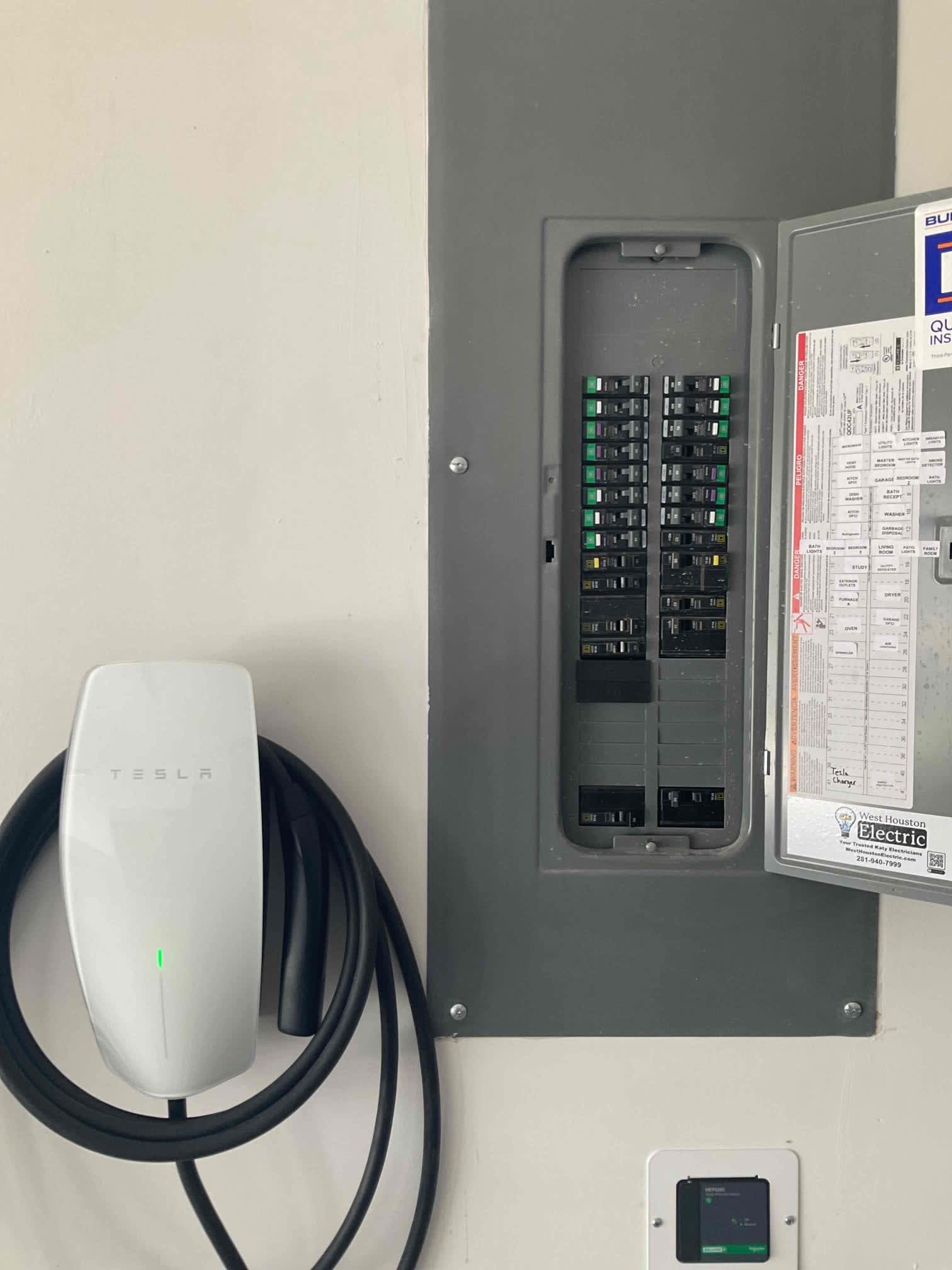 A clean, professional installation from West Houston Electric, Inc. shows organized breakers and a neatly mounted Tesla charger inspiring homeowner confidence.