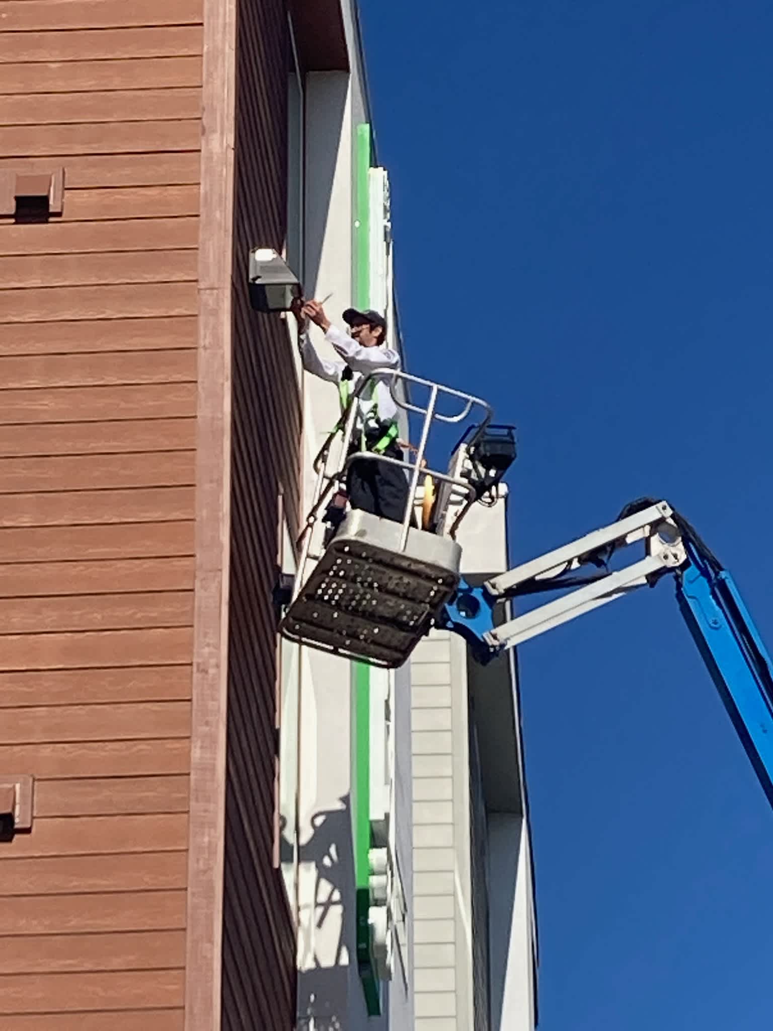 Skilled technicians from Abacus Plumbing, Air Conditioning, & Electrical safely handle exterior repairs from a lift, showing dependable craftsmanship.