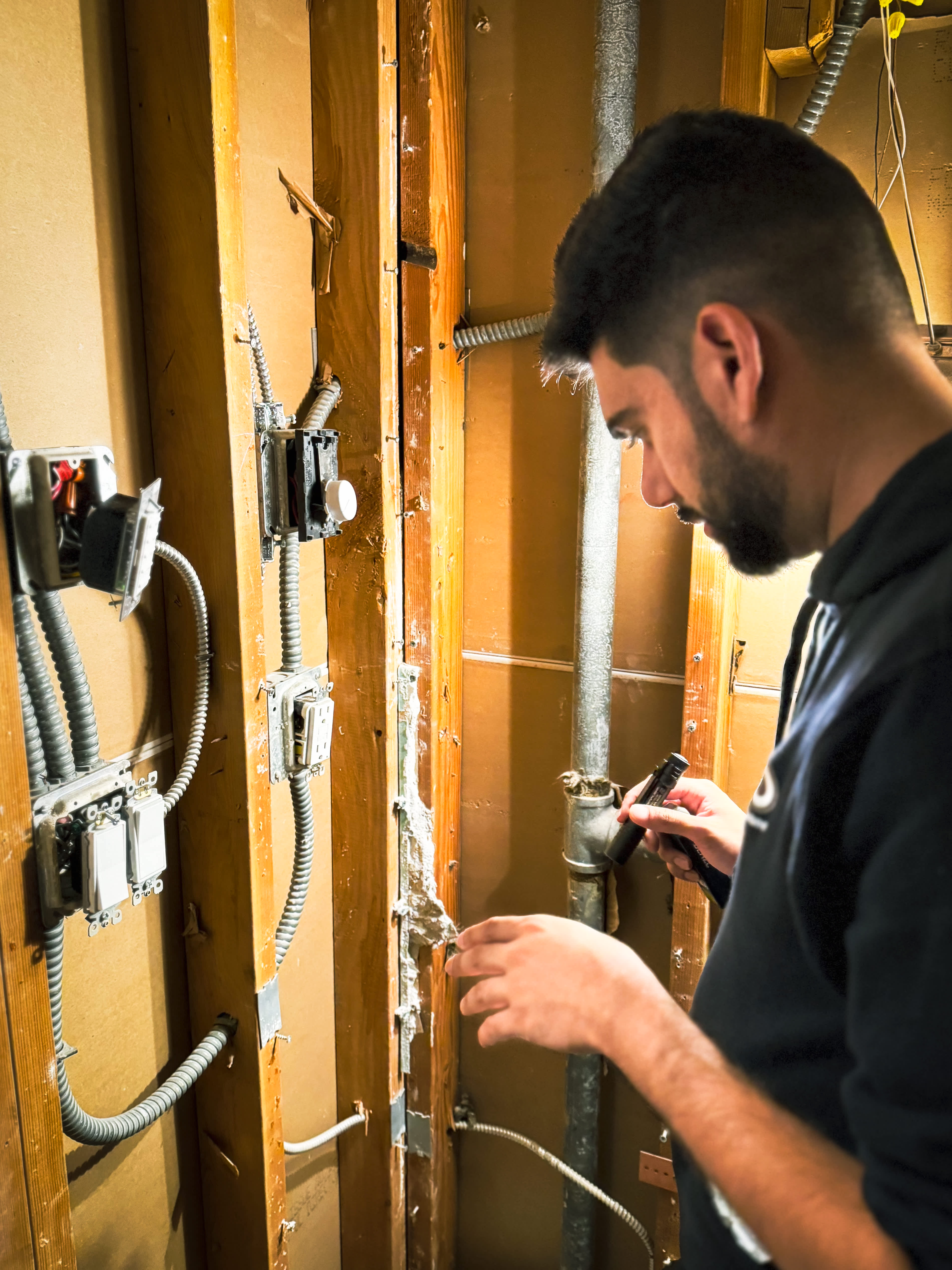 A focused technician from Eco Electric, Plumbing, Heating and Air inspects existing wiring and plumbing to ensure reliable, long lasting repairs.