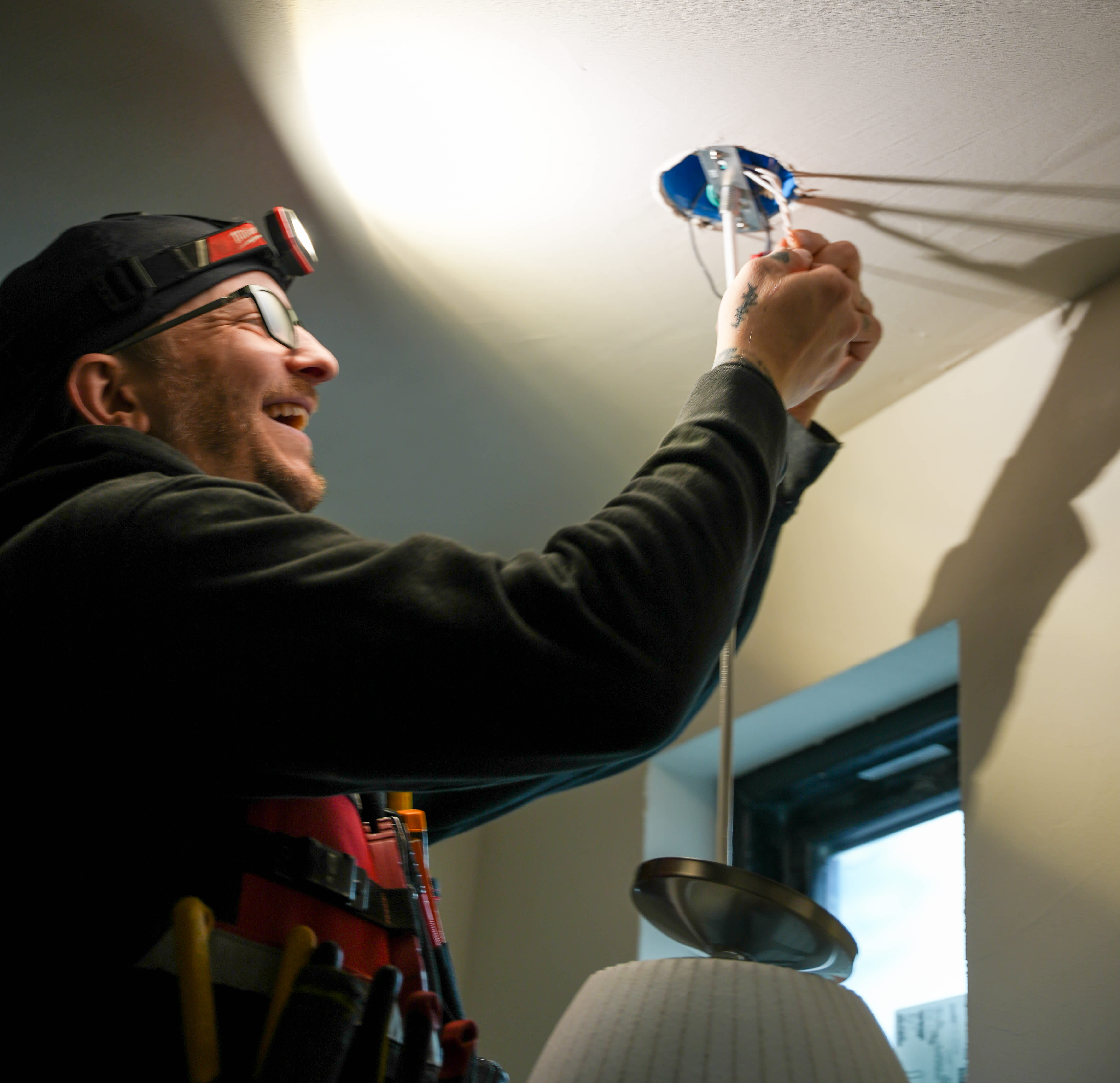 A skilled technician from Eco Electric, Plumbing, Heating and Air carefully installs a ceiling light, showcasing reliable craftsmanship and care.