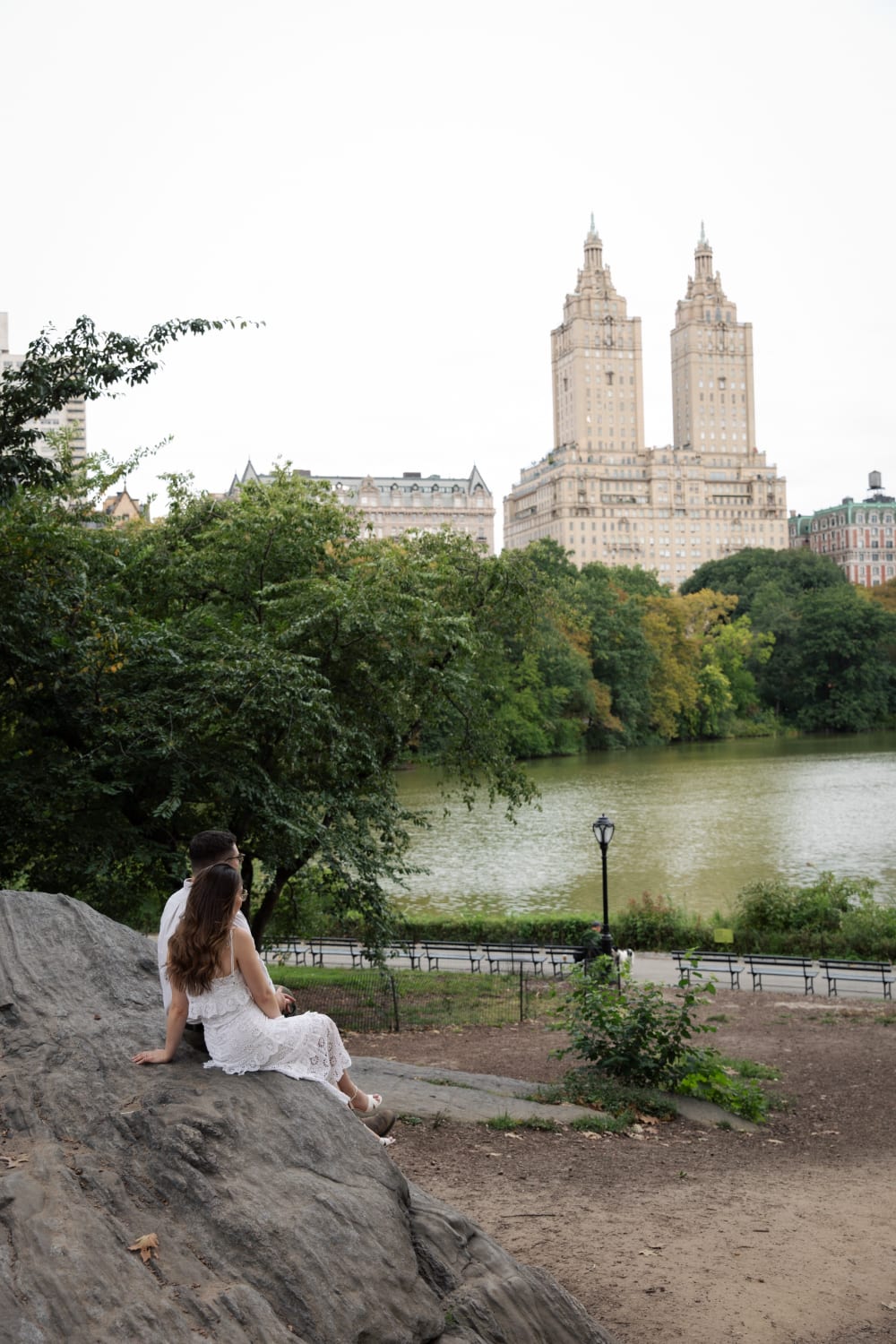 Sydney sitting on a rock above the Lake in Central Park with the San Remo towers behind her