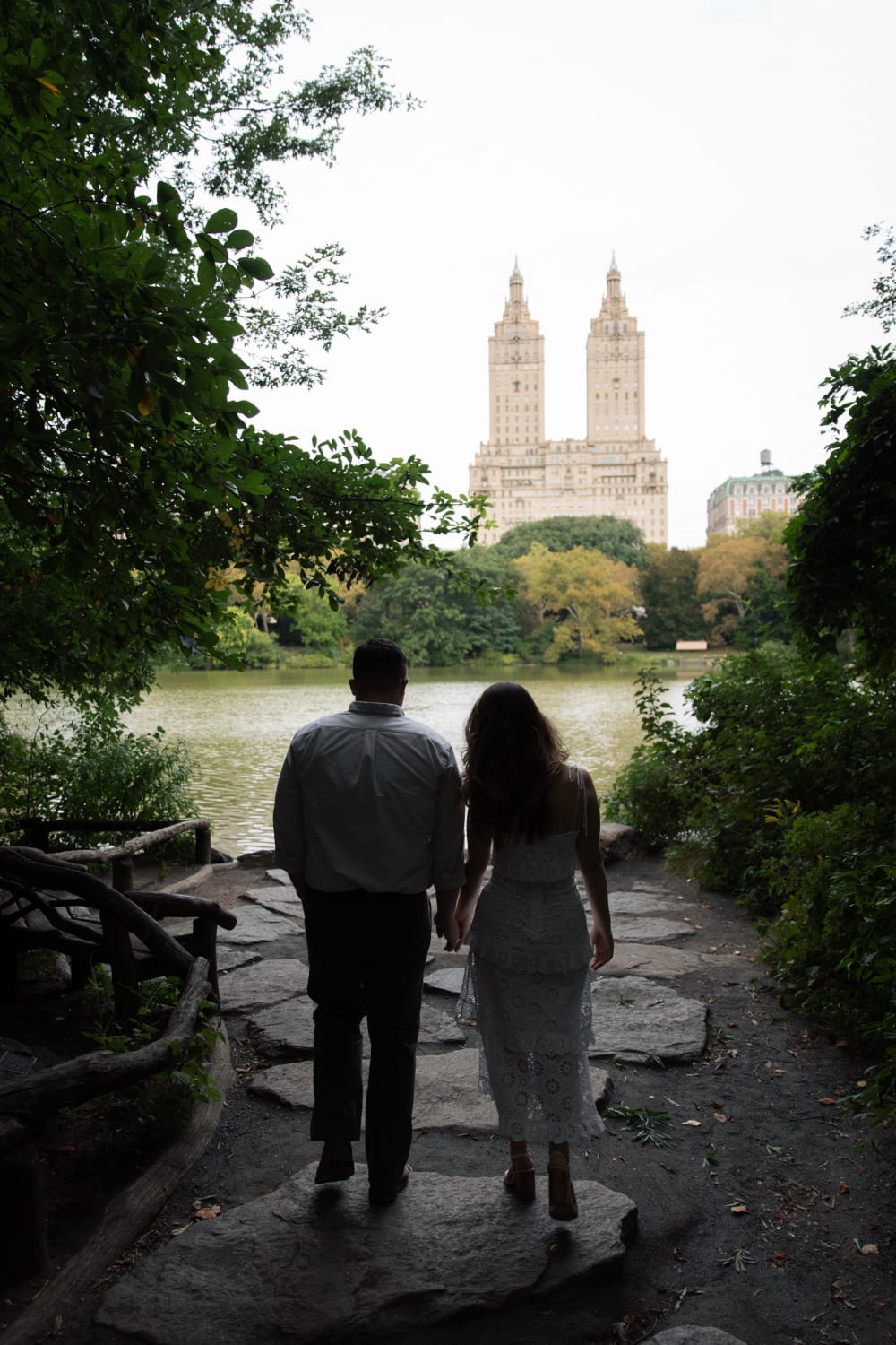 Sydney and Braden walking hand in hand along a stone path toward the Lake